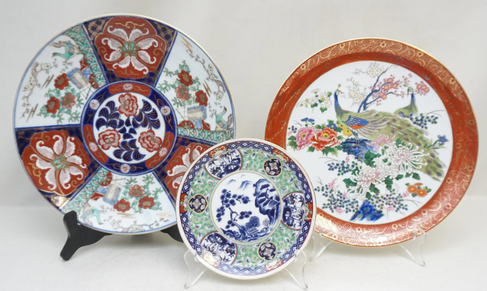 3 PC MID CENTURY JAPANESE PORCELAIN: All are Japanese Mid Century Porcelain Plates / Charger. 1- Imarii Charger. The large charger features a hand-embellished Imari design with cobalt blue and red flowers to the center and panels of outd