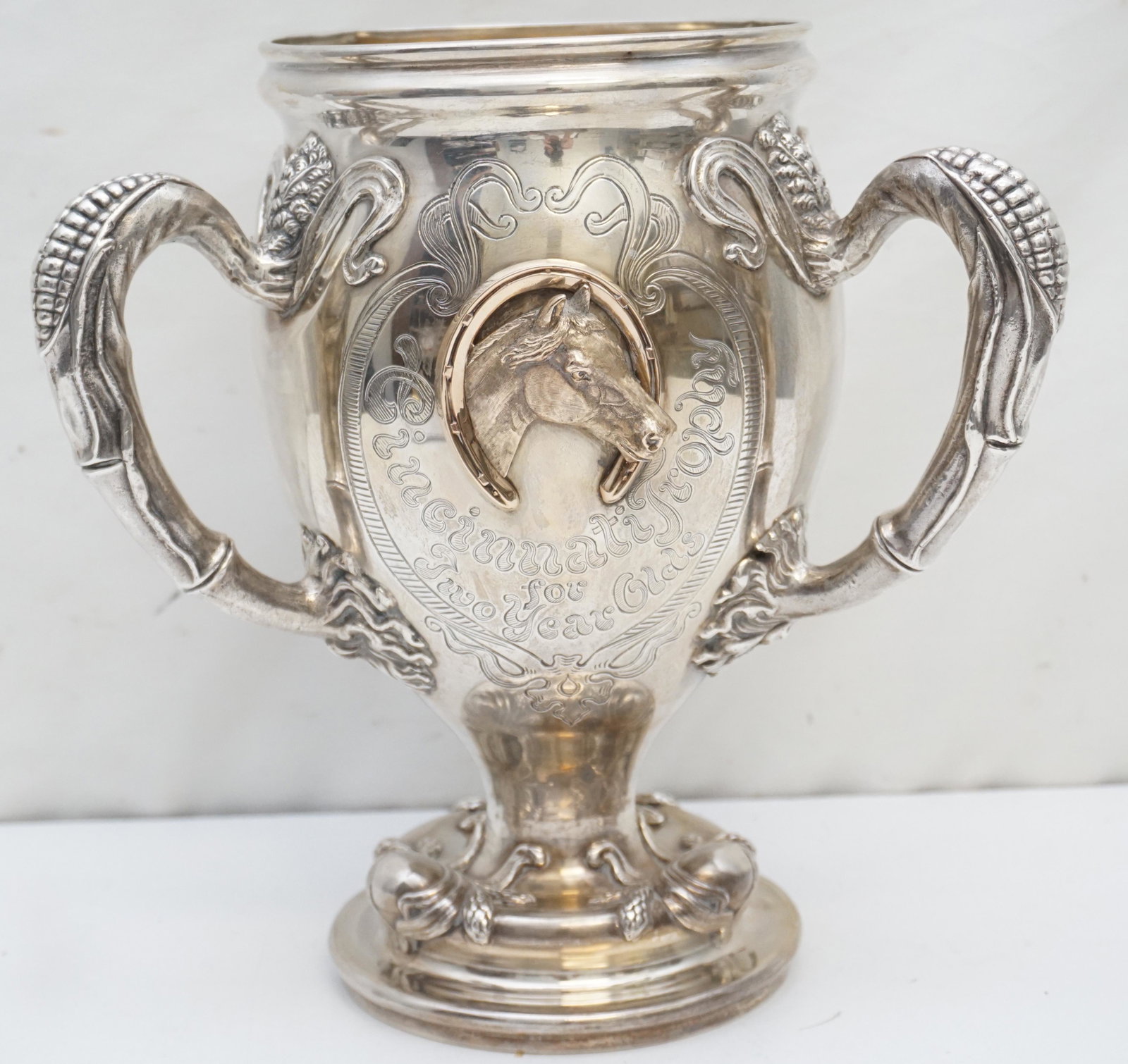 LARGE 1912 STERLING HISTORIC KENTUCKY TROPHY: . The Trophy was made by Theodore Neuhaus & Co., Gold & Silversmiths in Cincinnati . Ornate Cast Horse Head with Horseshoe. Figural Corn Handles. Engraved. On the bottom of the base is engraved Owned 