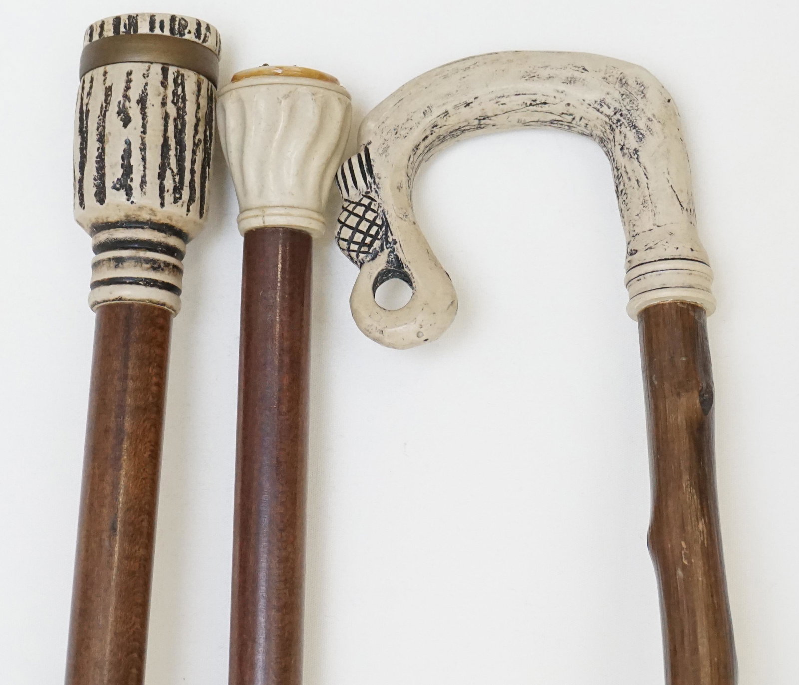 3 VINTAGE WALKING STICKS: Three composition faux antler walking stick / canes. 1 with compass top, 1 scrimshaw stag head, 1 with pineapple accent. All 32-34" long. Weight 2 ps 3 oz. PROVENANCE: A Charleston SC Private Estate.