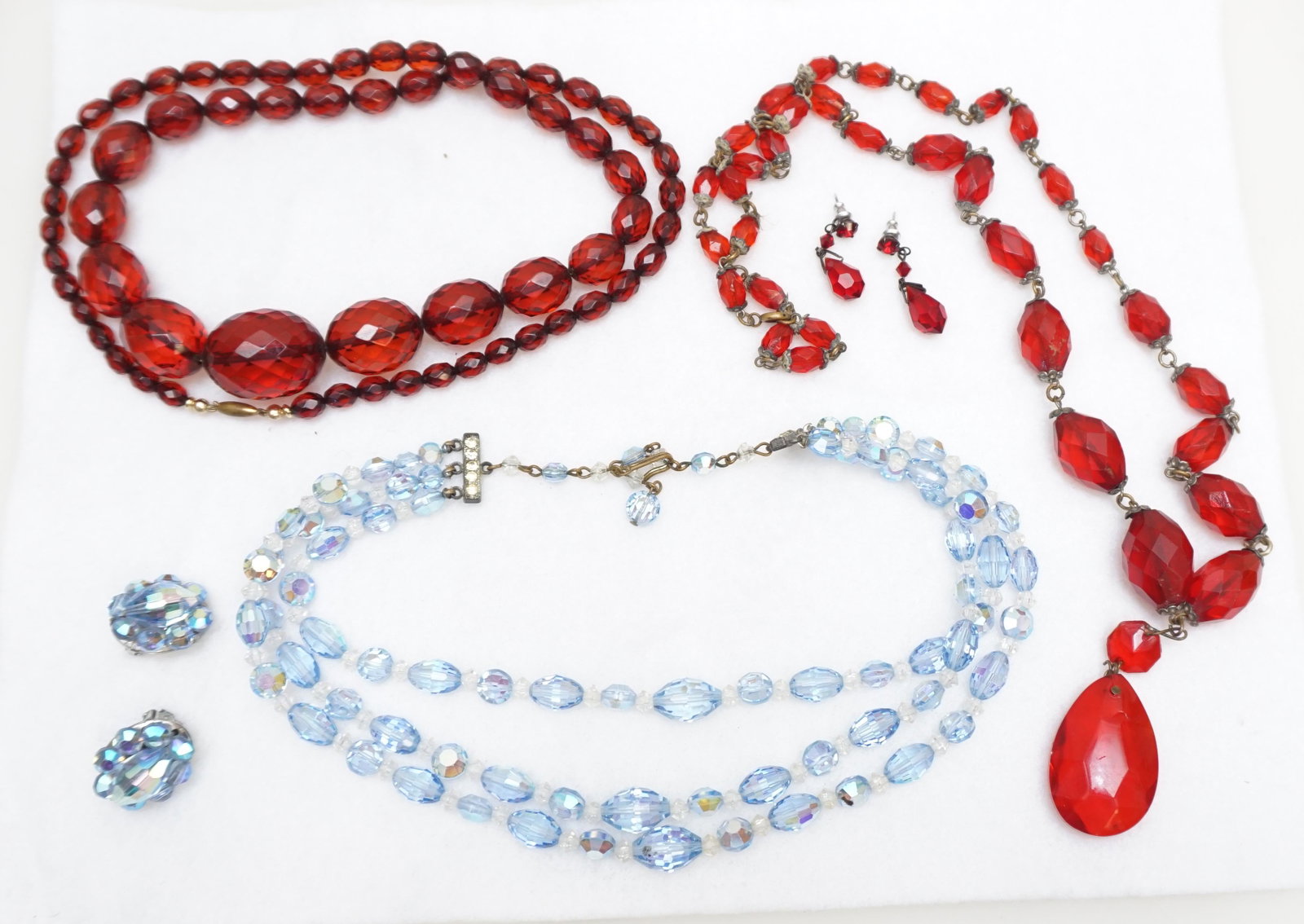5 pc AURORA BOREALIS + CZECH JEWELRY: All are Vintage. 1- Aurora Borealis Necklace and Matching Clip on Earrings. 2- Red Faceted Lucite Czech Necklace with teardrop shaped pendant 28" opened. 3- Graduated Red Bead Faceted Lucite Necklace 