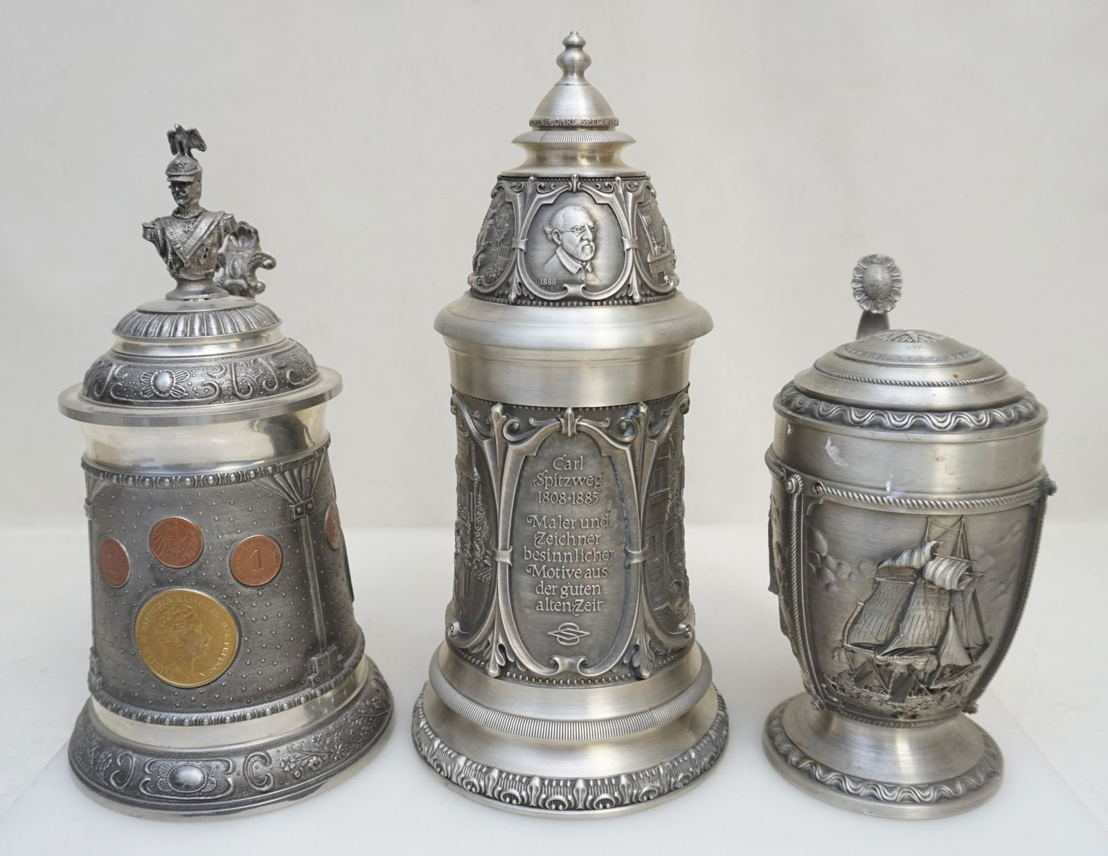 3 PEWTER BEER STEINS: 3 Collectible German Pewter Beer Steins. Mermaid Handle and Clipper Ship 7 3/4". German Coins 8 3/4".Carl Spitzweg 9 3/4". Weight on all 6 pds. .PROVENANCE: A Private Charleston SC Estate.