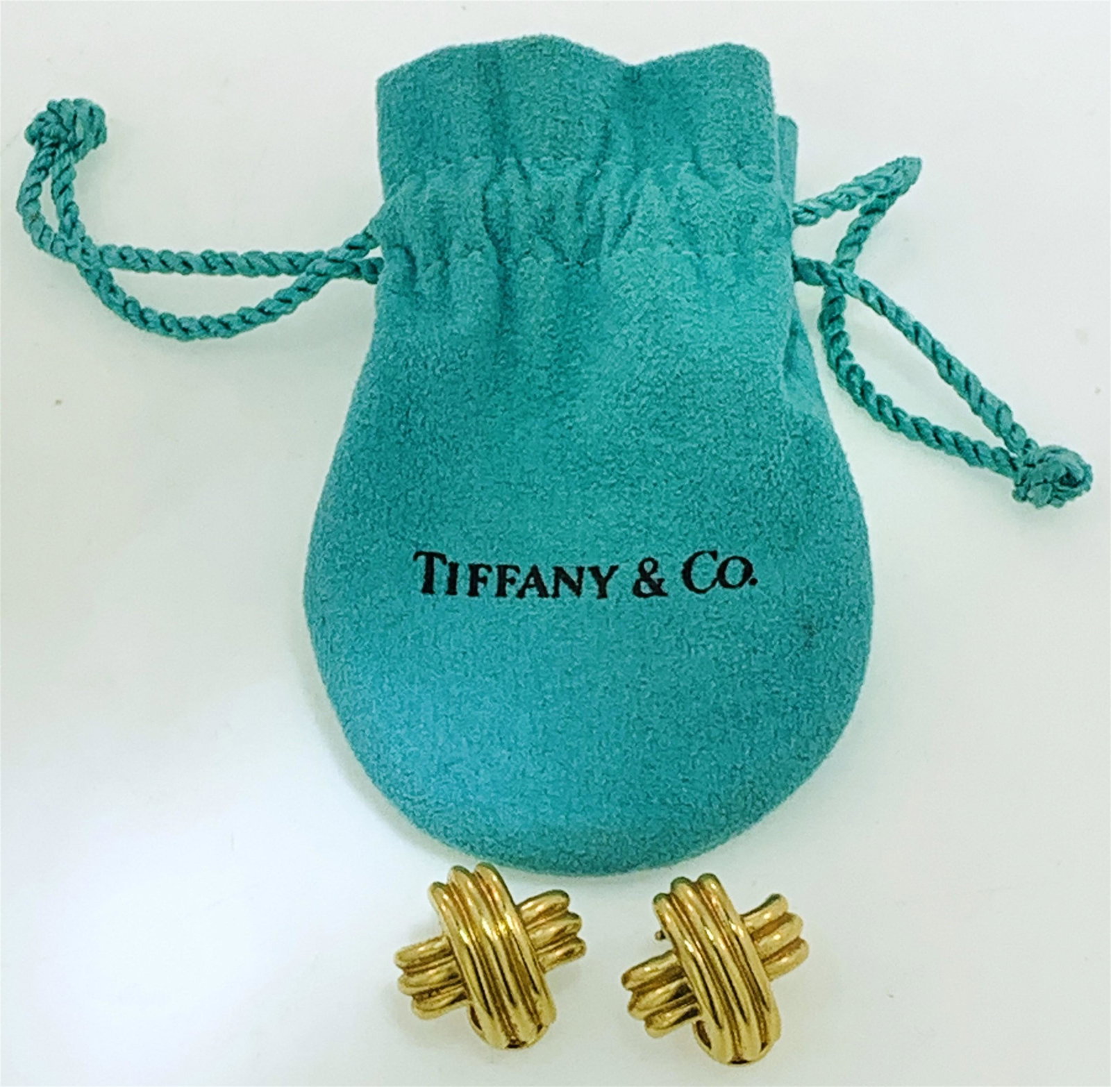 TIFFANY & CO. 18KT GOLD "X" STYLE EARRINGS (15.35: Pair of 18kt Tiffany & Co. "X" style clip on earrings with bag. The earrings have a triple ridge, measure approx. 19.20 x 19.55 mm, have omega clip on backs, a high polish finish, are marked "T & Co 7