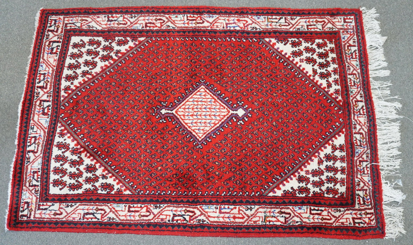 SEMI ANTIQUE HAND KNOTTED BOKHARA RUG: Semi Antique Hand Knotted Fine Bokhara Carpet. Pakistani, repeating rows of guls on central panel with center medallion , multiple borders, reds, blacks and cream highlights. Missing fringe one side. 
