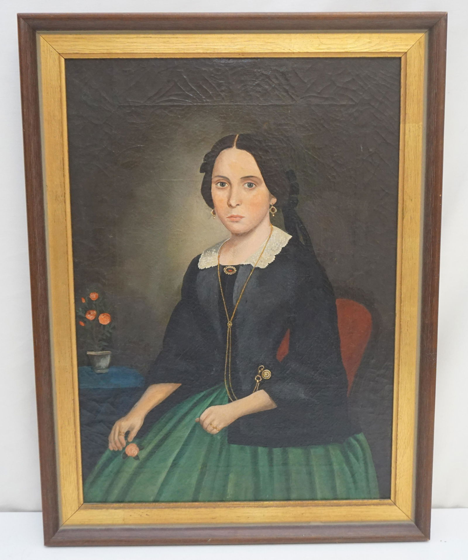 19TH c SOUTHERN SCHOOL OIL ON CANVAS PORTRAIT: Portrait of a Woman in a black jacket with green skirt, oil on canvas, unsigned, having lace collar, gold and garnet jewelry, gold rings, her hair in a black ribbon, seated in a balloon back chair, ho