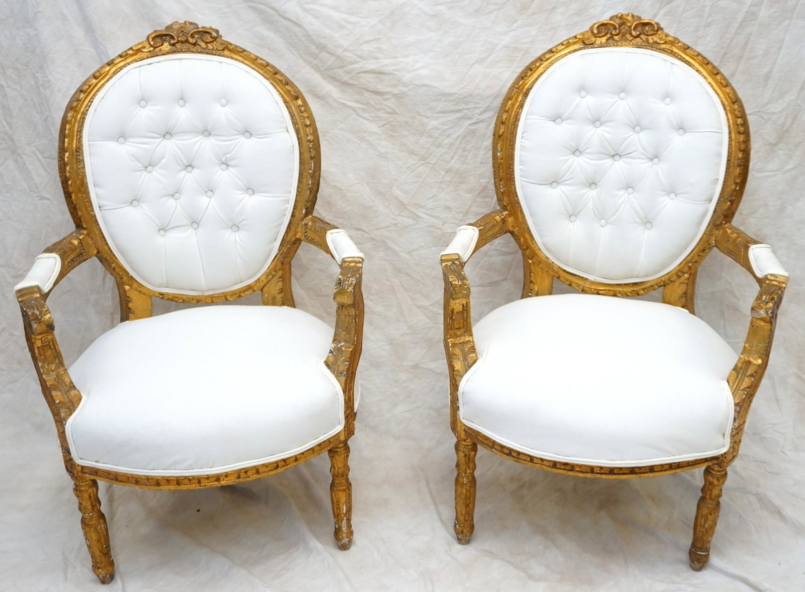 PAIR FRENCH CARVED AND GILDED ARM CHAIRS: Pair of Antique Carved Gilt Wood Arm Chairs. Reupholstered in a heavy linen with tufted backs. Some minor wear to each. Each 26" wide x 24" Deep x 41" high. NO IN HOUSE SHIPPING. PROVENANCE: A Private