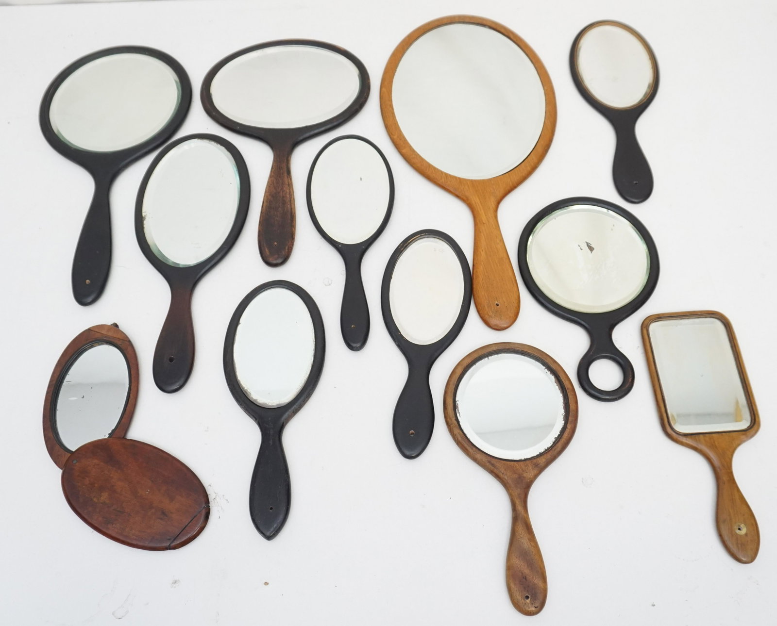 12 ANTIQUE AMERICAN SHAKER HAND MIRRORS: 11 Antique American Shaker Carved Hand Mirrors amd 1 small travel mirror from France. All the Hand Mirrors have the original beveled glass. These were displayed in a group along one wall and all have 