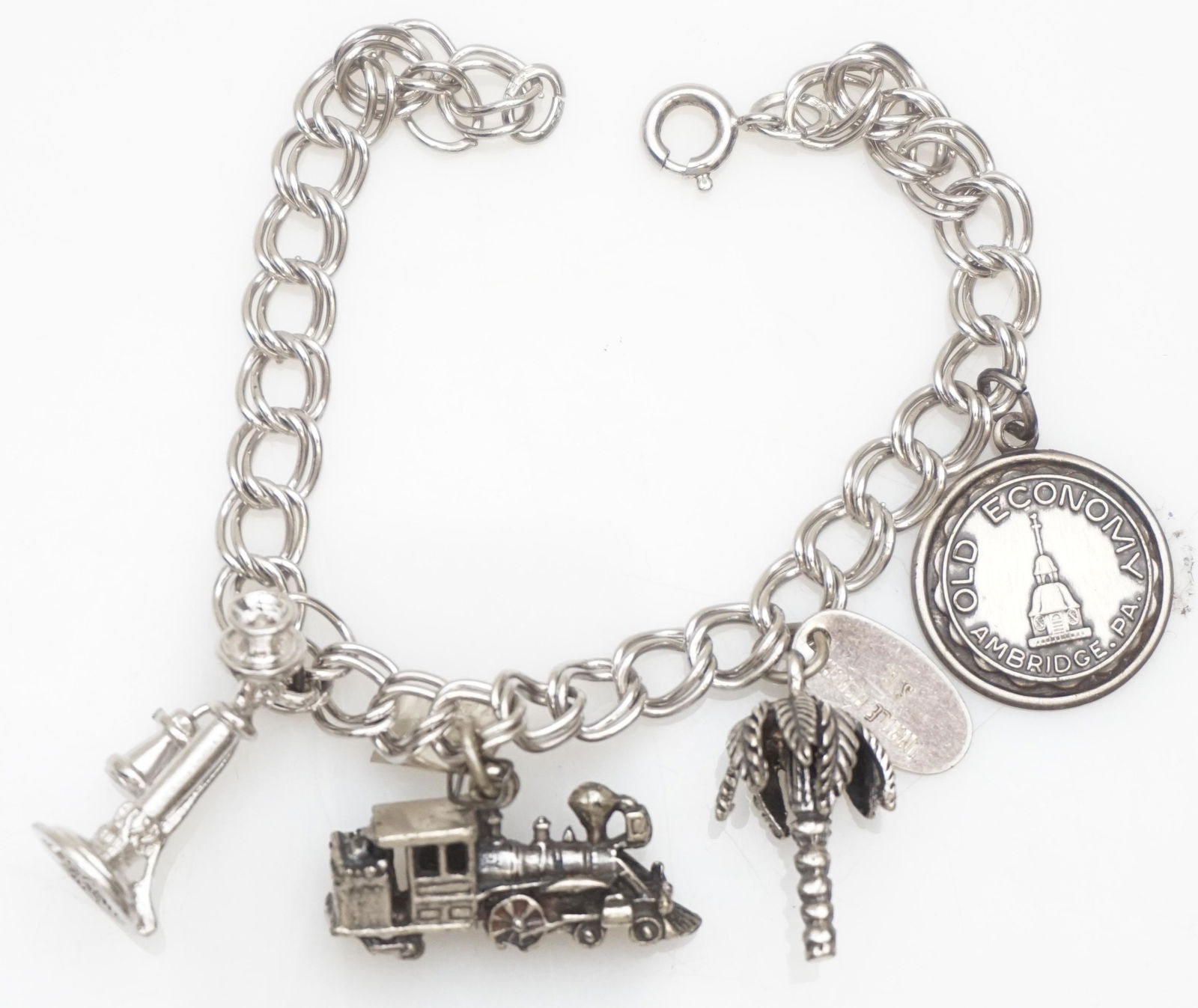 STERLING SILVER 7" LINK CHARM BRACELET: One sterling silver 7.00" double link charm bracelet featuring four (4) charms- 1- old economy ambridge PA, 2- Myrtle Beach Palmetto tree, 3- Pennsylvania Train Engine, 4- Candlestick telephone. The b
