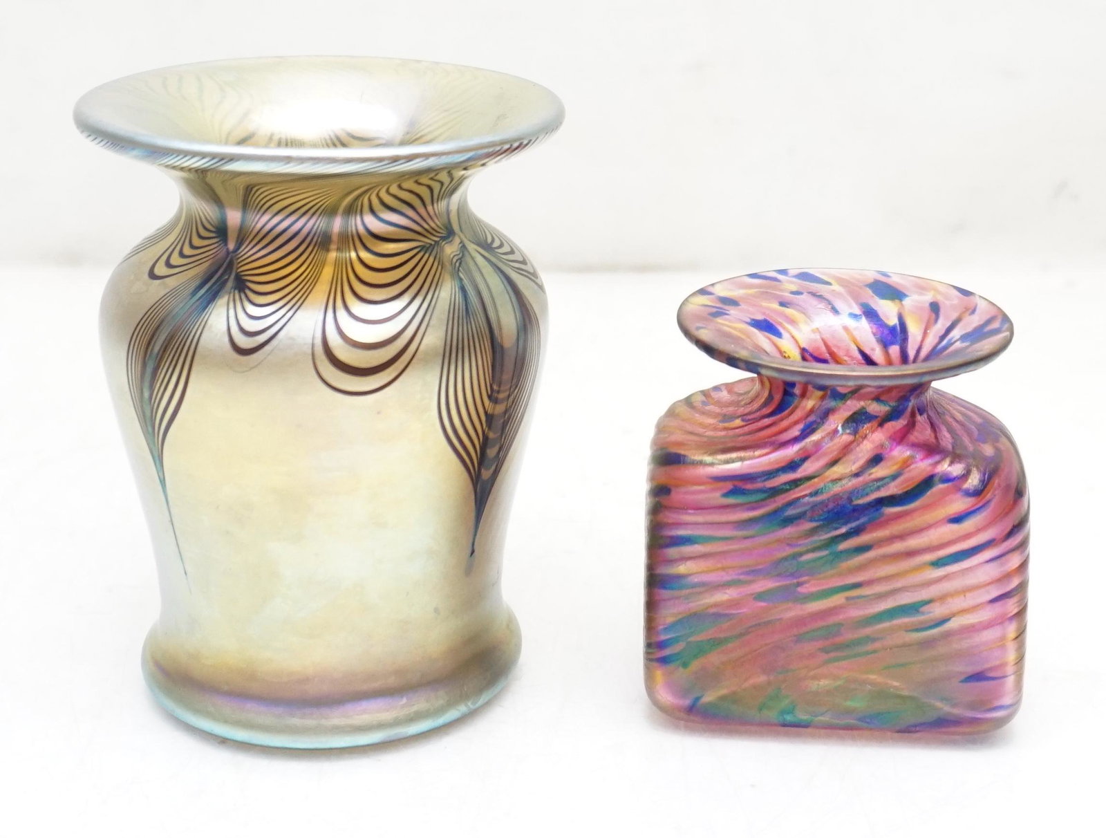 2 ROBERT HELD & ZEPHYR ART GLASS - SIGNED: 1- Robert Held Signed Small Iridescent Bud Vase in Purple Gold and Blue 2 1/2"x2 3/4". 2- Zephyr Glass Works Signed and Dated 1985 Gold Iridescent Pulled Feather Vase 3 1/4"x3 1/4"x4 1/4". Weight on b