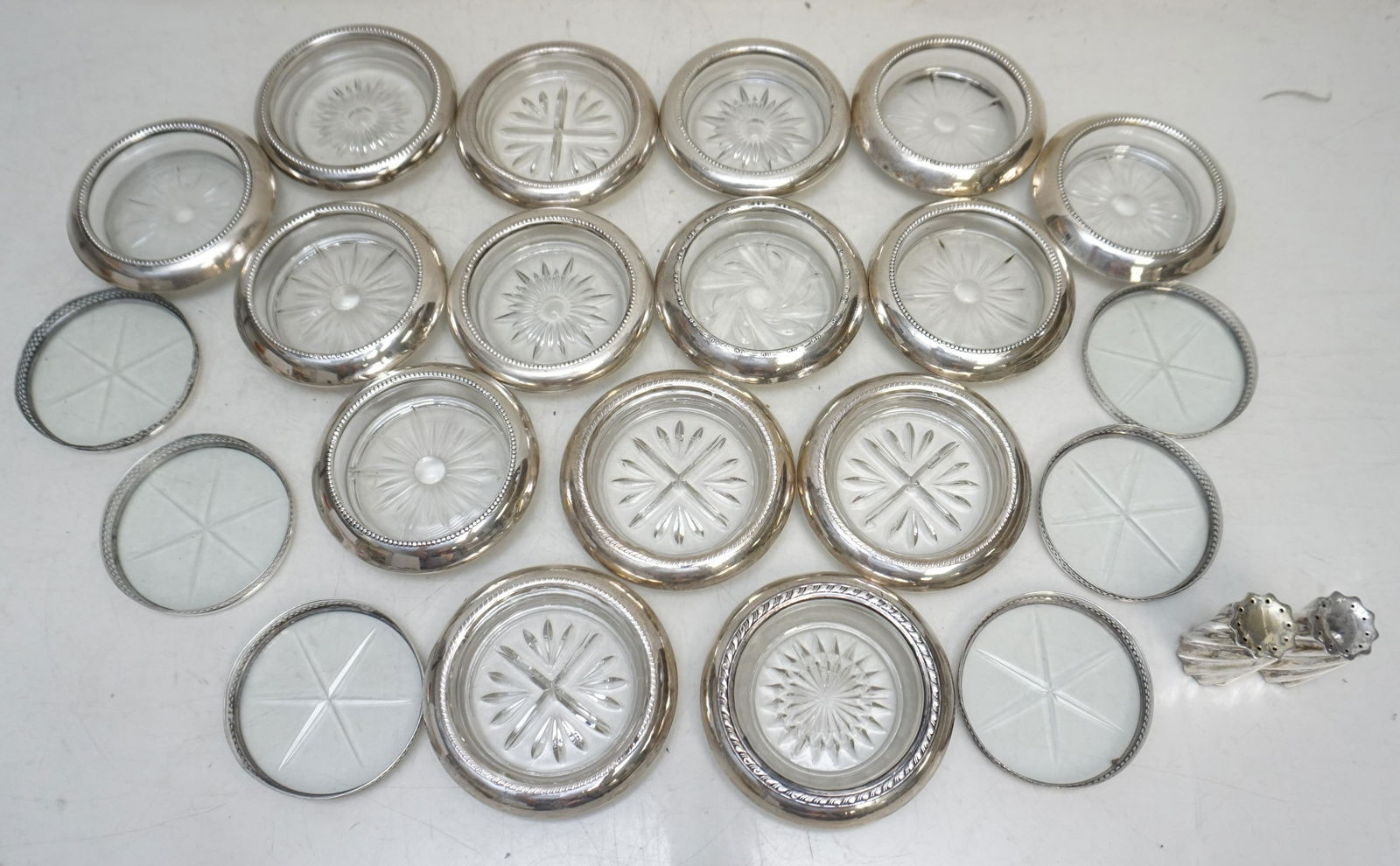 22 PC AMERICAN STERLING SILVER COASTERS +: 21 Vintage American Sterling Silver Rimmed Glass Varied Coasters and 1 Towle Sterling Salt & Pepper. Makers include Frank M. Whiting, Roger Brothers and others. Weight on all combined 5 pds 14 oz. PRO