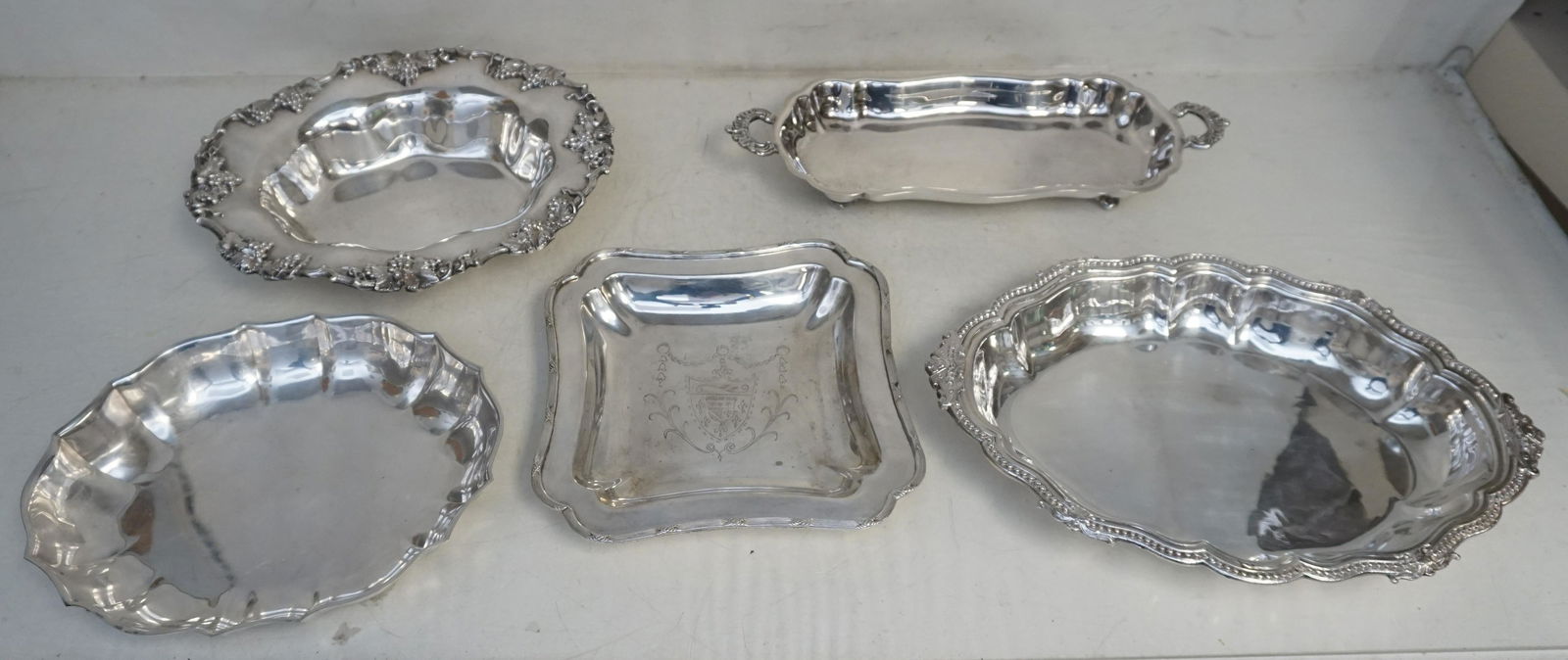 5 PC VINTAGE SILVER PLATE BOWLS - SERVING TRAYS: All are Vintage/Antique Silverplate. 1- English Armorial Coat of Arms Square Dish 8 1/2". 2- James Dixon Sheffield Scalloped Oval Bowl 13 3/4". 3- Rogers Scalloped Bowl 10 1/2". 4- Chased Grape Border