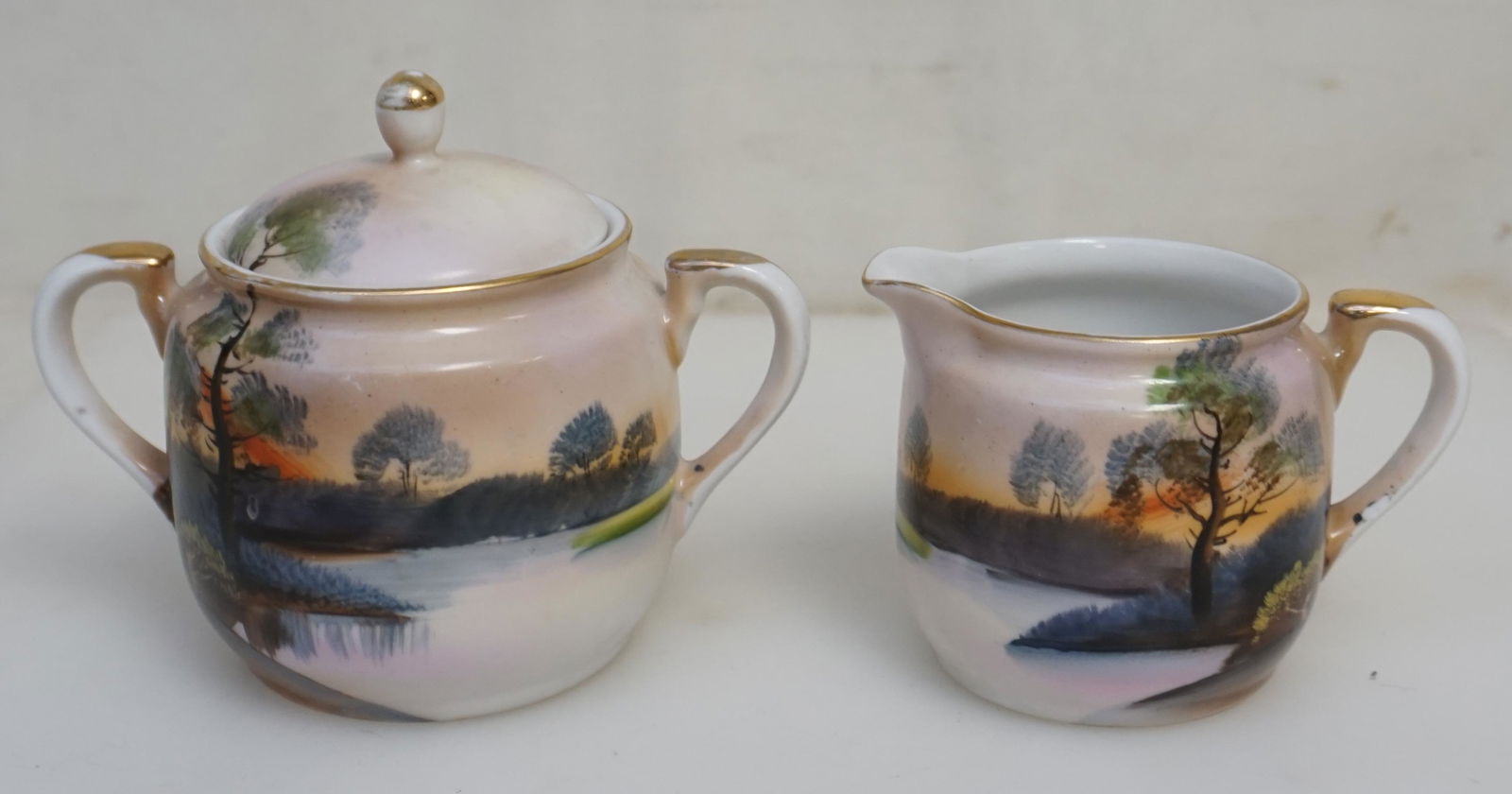 HAND PAINTED LANDSCAPE CREAM & SUGAR NORITAKE: Noritake hand painted Landscape Cream and Sugar Set c. 1920s.. With green "M" wreath mark used from 1918. Sugar 4 1/4" and Cream 3". Weight combined 12 oz. PROVENANCE: A Private Charleston SC Estate