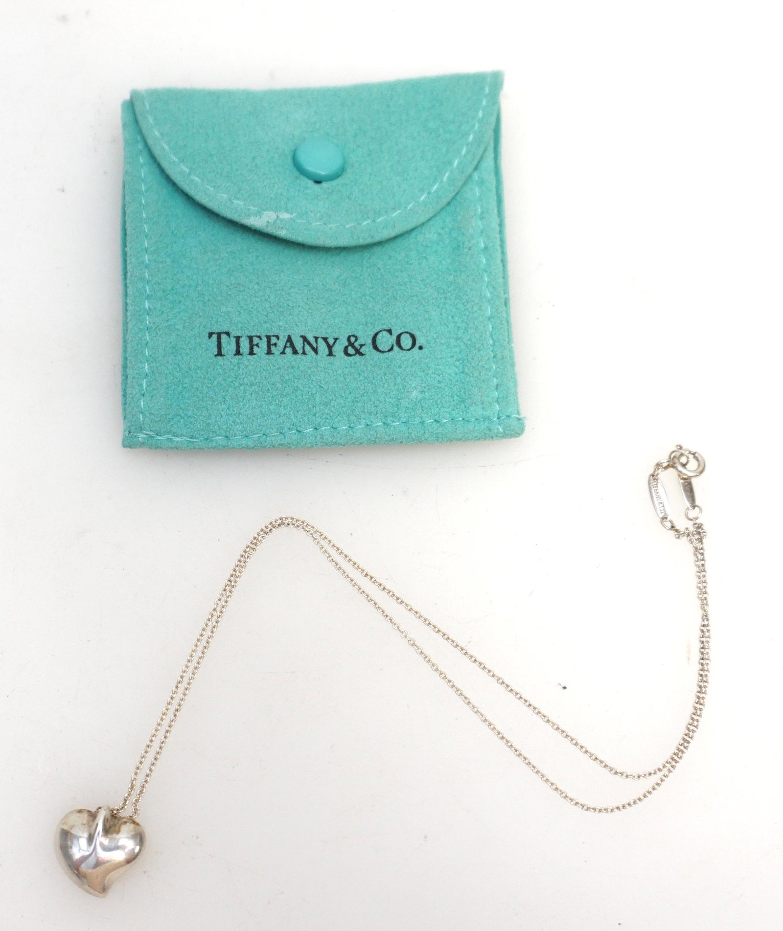 TIFFANY ELSA PERETTI STERLING HEART NECKLACE: Beautifully cast in sterling silver, this necklace is from the 'Carved Heart' collection of legendary jewelry designer, Elsa Peretti for Tiffany & Co. Chic and elegant in design, the stylized concave 