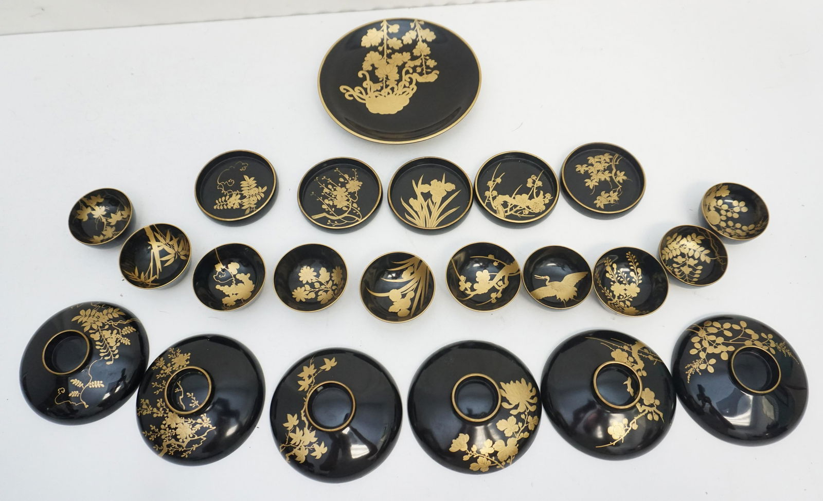 22 pc JAPANESE BLACK LACQUER GROUPING: 22 Piece Vintage Japanese Black Lacquer with hand Painted Gilt Florals. Including 6 Shallow Footed Bowls 4 1/4". 1 Plate 6 3/4". 5 Wine Coasters 3 1/4". 10 Sake / Tea Bowls 2 1/2"x1". Weight on all 1