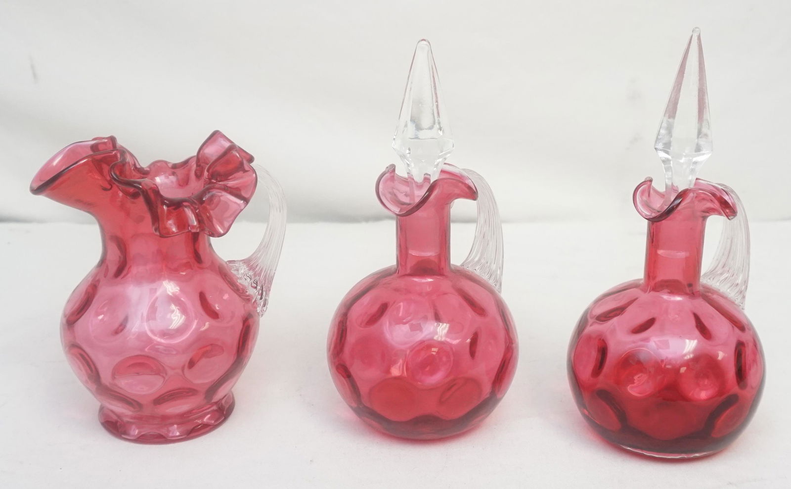 3 pc VTG CRANBERRY CRUETS & PITCHER: 1940's Vintage Fenton LG Wright Large Cranberry Glass Dot Optic (Thumbprint) 2 Cruets 7 1/2" to top of stoppers and 1 Jug / Pitcher 5 1/2". Weight on all 2 pds 7 oz. PROVENANCE: A Charleston SC Privat