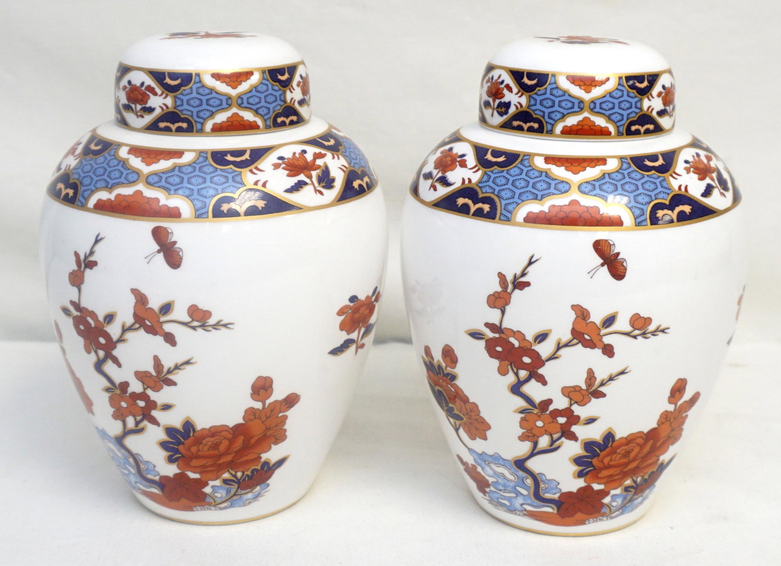 PAIR SPODE SHIMA GINGER JARS: Pair of Spode fine china ginger jars in the Shima pattern. The white lidded jar features a chinoiserie inspired red and blue floral motif with a blue and red border and gilt trim. The jar is marked â