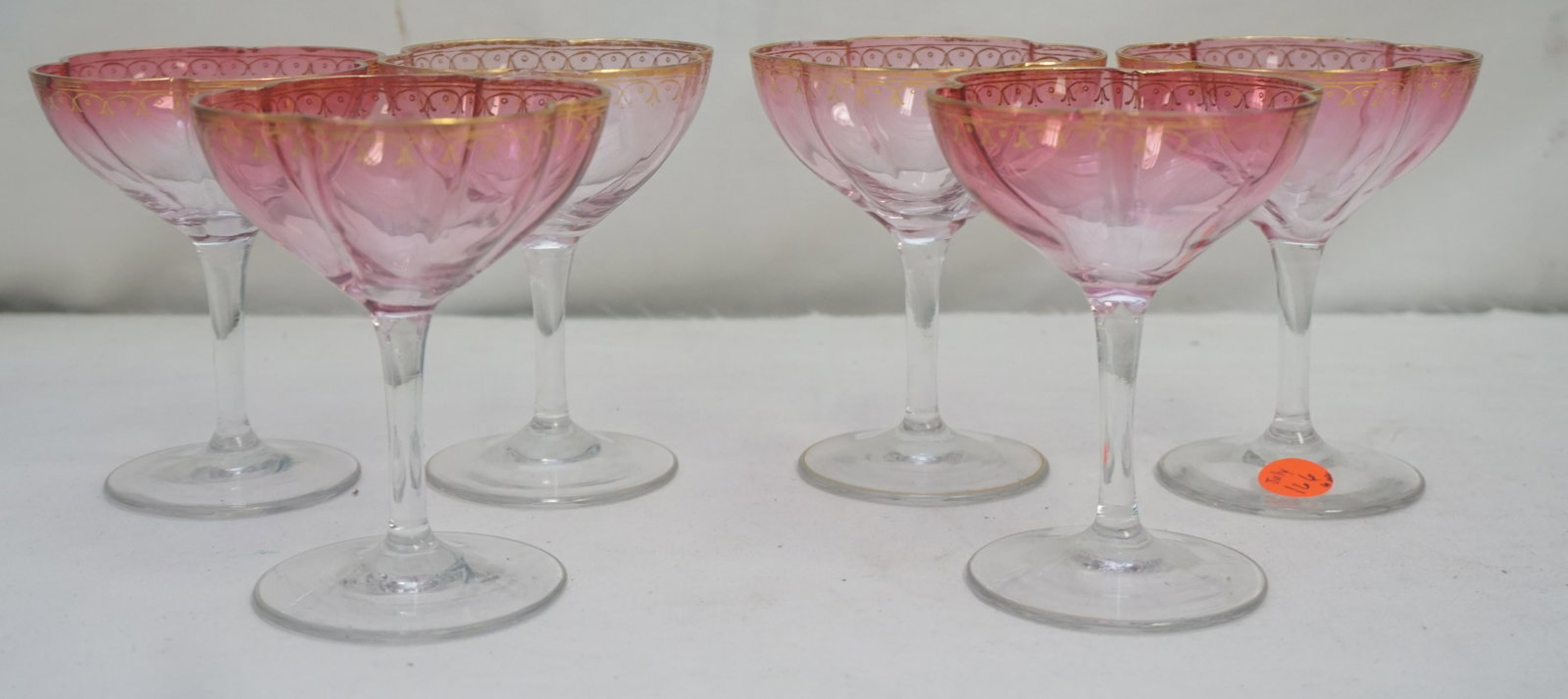 6 ANTIQUE PINK FLORIFORM CHAMPAGNES: 6 Crystal Pink to Clear Floriform Champagne Glasses attributed to Lobmeyr. Gilt accents. Minor wear to gilt 3 with nicks to tim. Weight on all 1 pd 8 oz. PROVENANCE: A Private Charleston SC Estate.
