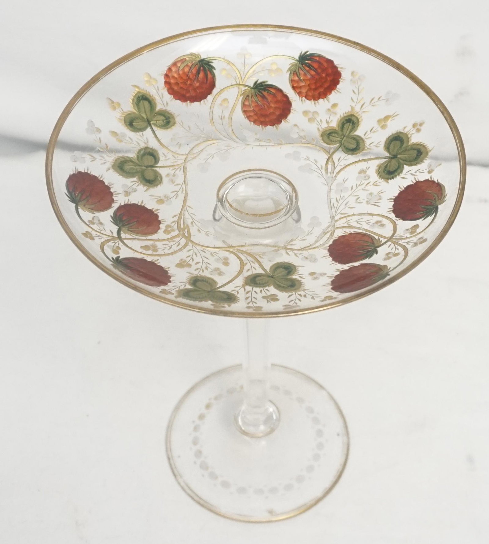 ANTIQUE ENAMELED TAZZA RASBERRIES: Antique c. 1900 long stem Bohemian tazza, skillfully intaglio cut and polychrome gilded with raspberry clusters, leaves and swirling stalks; gilt bands are applied around the rim and central knop. The