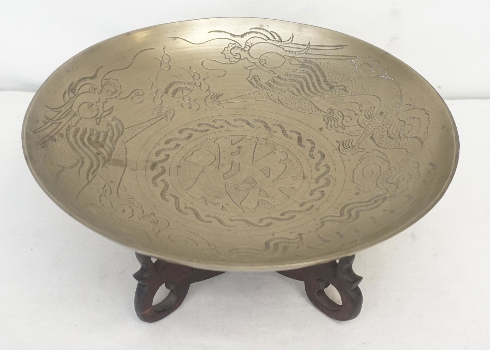 LARGE CHINESE BRASS BOWL WITH CARVED WOOD STAND: Decorative Vintage Chinese brass bowl with etched dragon motifs on the interior surface. Interior surface Center emblem has etched Asian characters. With carved Rosewood Stand. Bowl 12". Weight on all