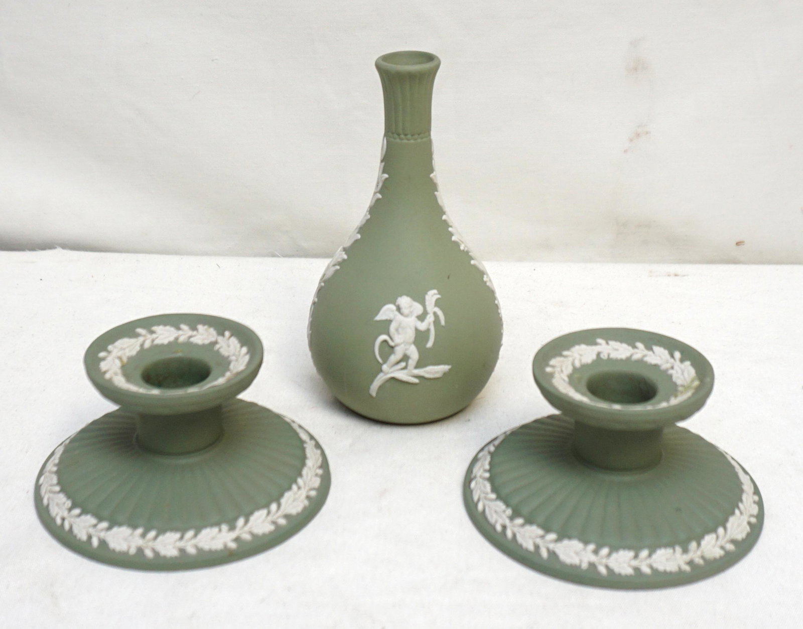 3 pc WEDGWOOD GREEN JASPERWARE: 3 Piece Vintage Wedgwood Green Jasperware. Incluse Vase 5 1/2" and a Pair of wide base Candlesticks 4" wide 2 1/4" tall. Weight on all 1 pd 2 oz. PROVENANCE: The Estate of Dr. Fraser Wilson, Charlesto