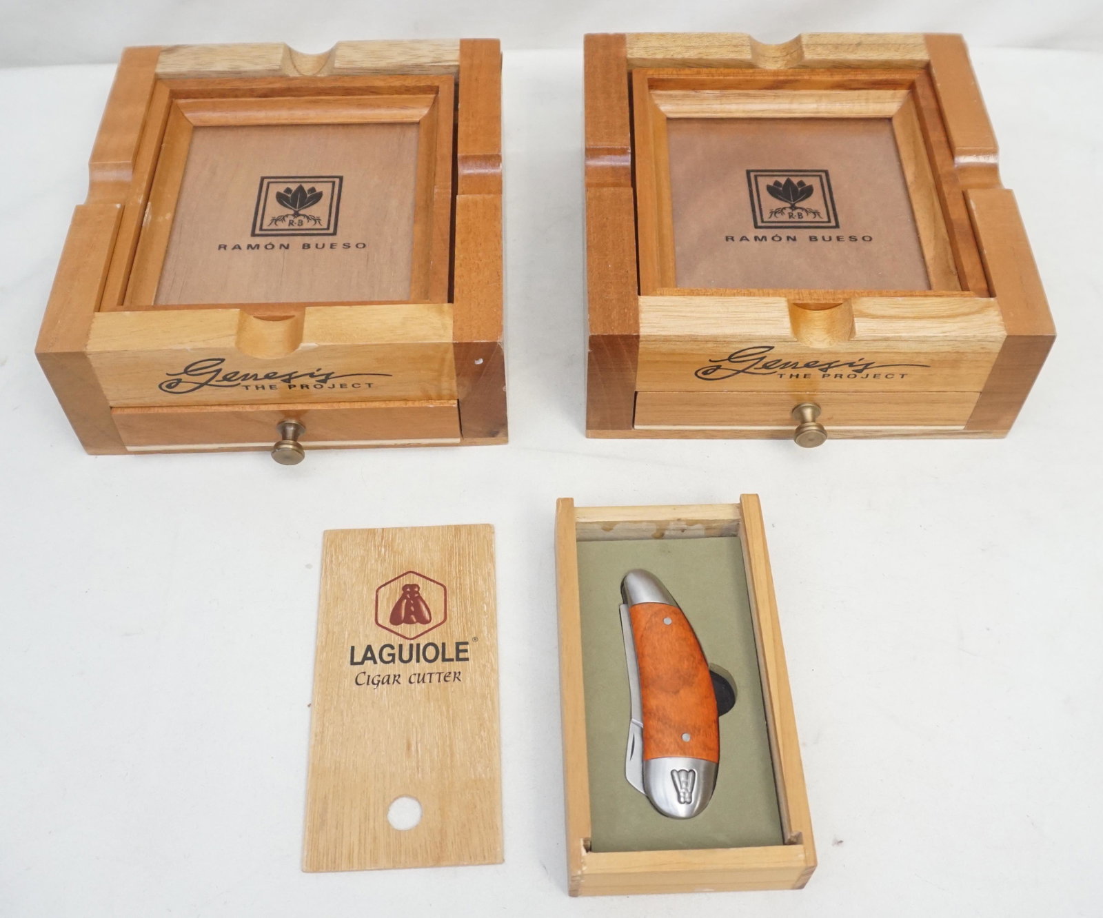FORGE DE LAGUIOLE CIGAR CUTTER & CIGAR ASHTRAYS: Two Ramon Buesi Genisis wooden cigar ashtrays and a Laguiole cigar cutter. Total weight 3.5 lbs. Inhouse shipping not guaranteed on this lot.