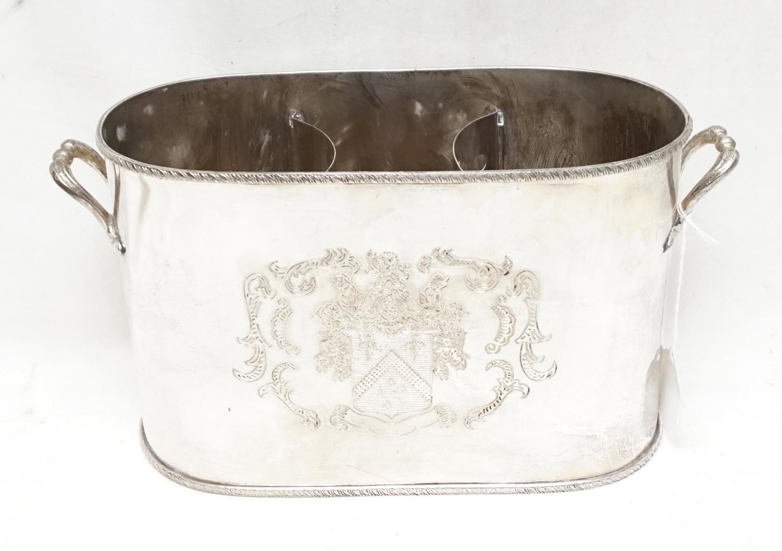 DUAL HANDLED SILVER PLATED ARMORIAL WINE COOLER: Contemporary. Double handled silver plated wine cooler having a coat of arms to each side, two-compartments with removable dividers and gadrooned edges. Crossed keys hallmark and marked EP. Approx. h.