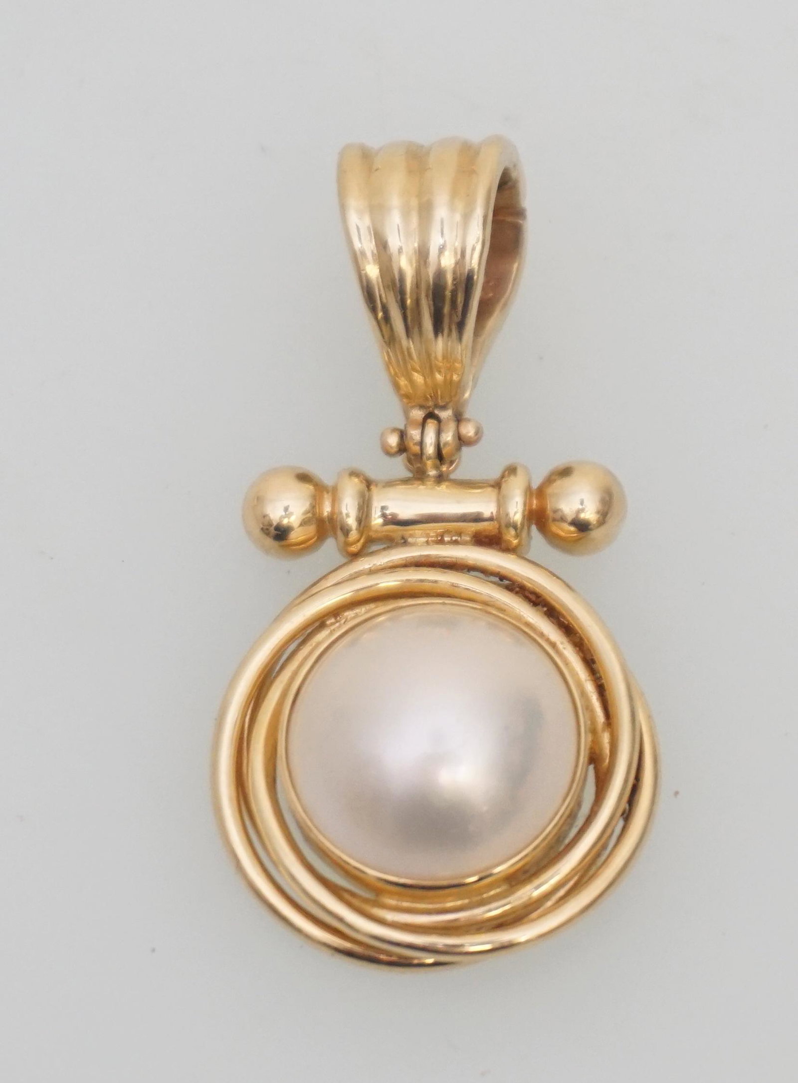 14KT GOLD MABE PEARL PENDANT/PEARL ENHANCER: Beautiful 14kt gold mabe pearl enhancer. The piece features one (1), bezel set, mabe pearl measuring approx. 13.60mm set in the center of a tri banded border below a bar/ball accent and a fluted bail.