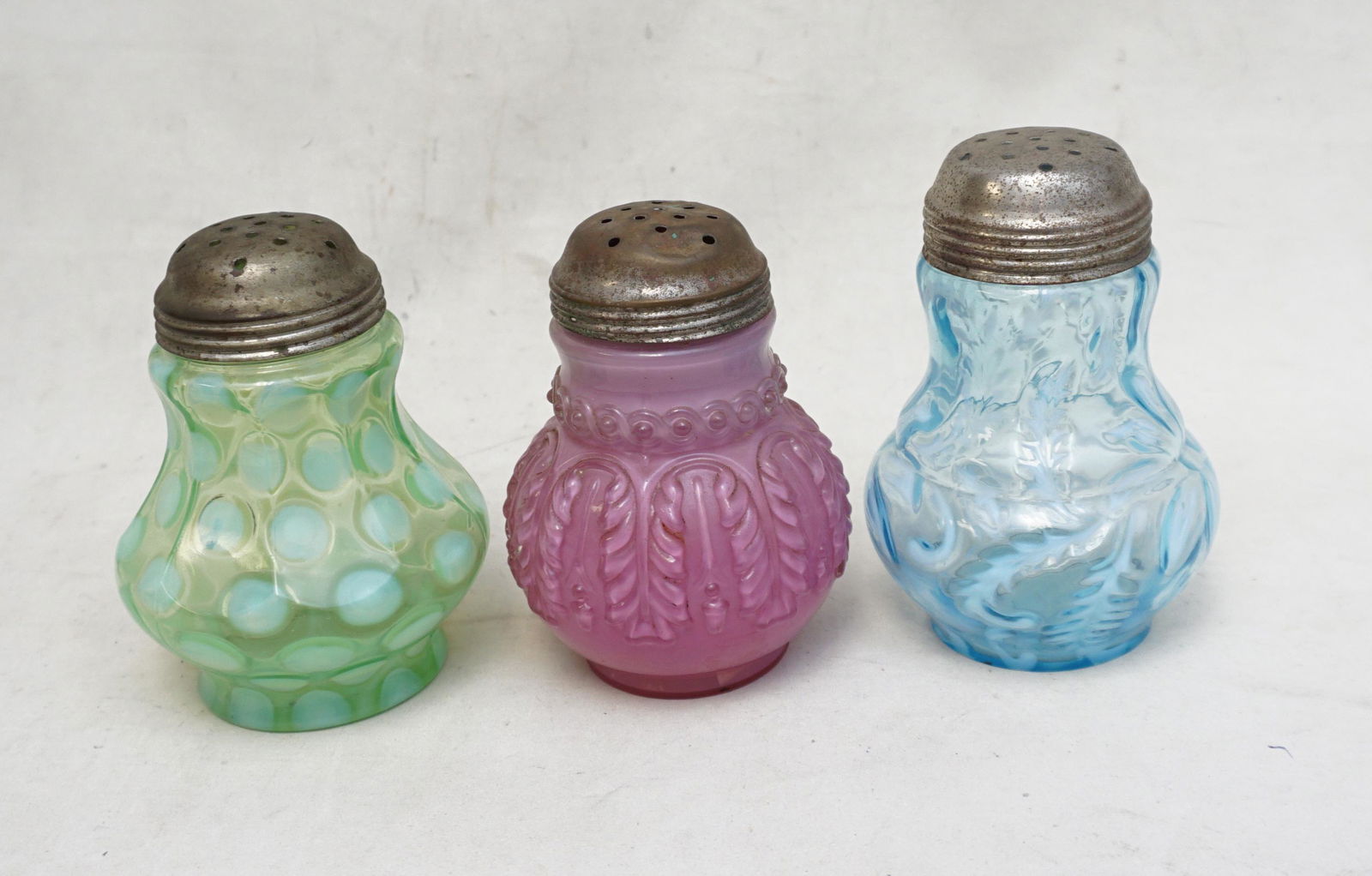 3 ANTIQUE NORTHWOOD GLASS SUGAR SHAKERS: All are Antique American Northwood Glass. All with original period tops. 1- Northwood Leaf Umbrella in cased Rose du Berry. A Bulbous based shaker that exhibits a hanging Leaf and flower bud pattern a