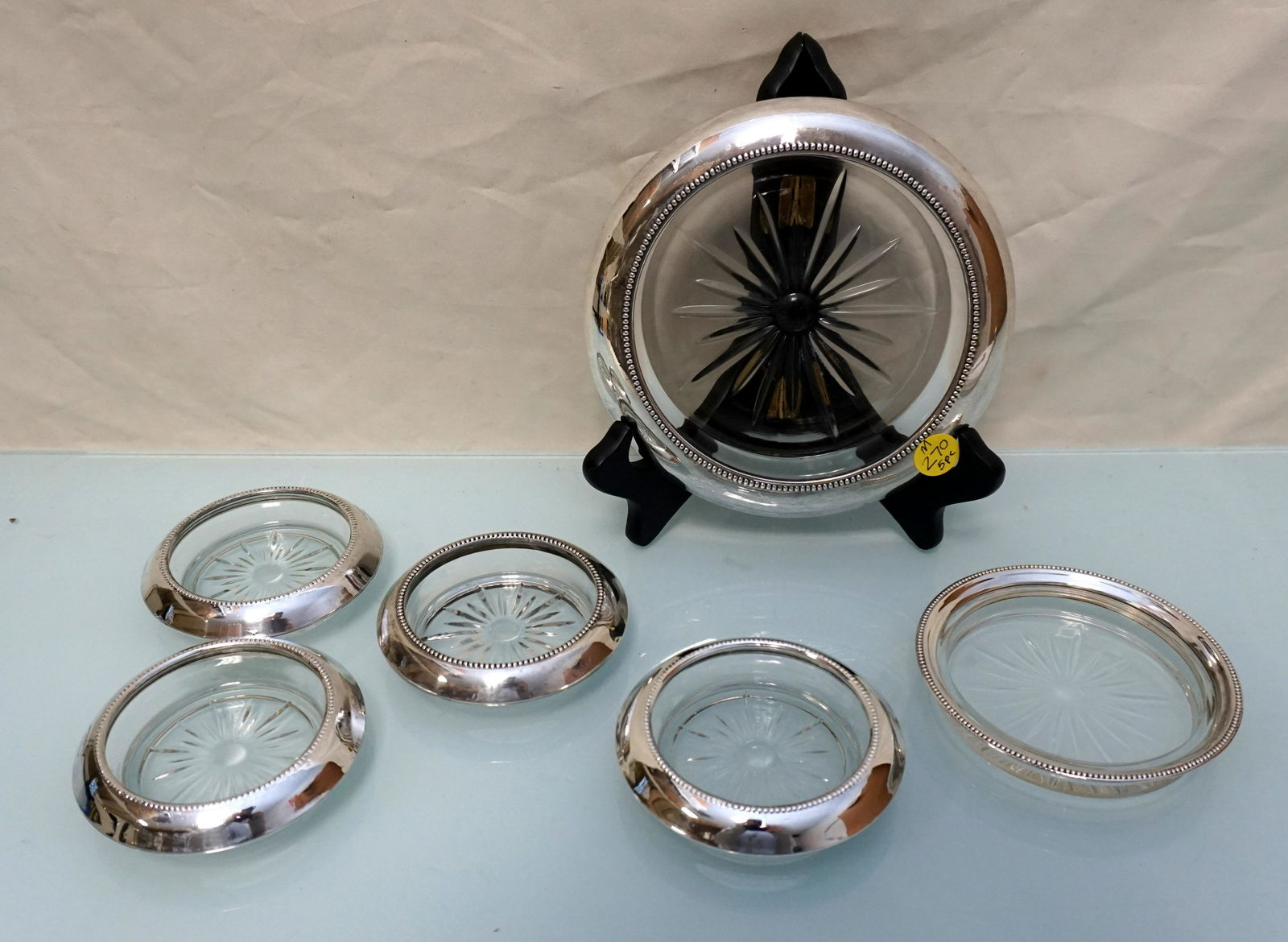 6PC GLASS & STERLING RIMMED GLASS COASTERS: Two Frank M. Whiting Sterling Rimmed Wine / Champagne Bottle Coaster 6 3/4" and 4 1/4". 4 Frank M. Whiting sterling Rimmed Glass Coasters. 3 1/2". Weight on all 3 pds 3 oz. PROVENANCE: A Charleston Pr