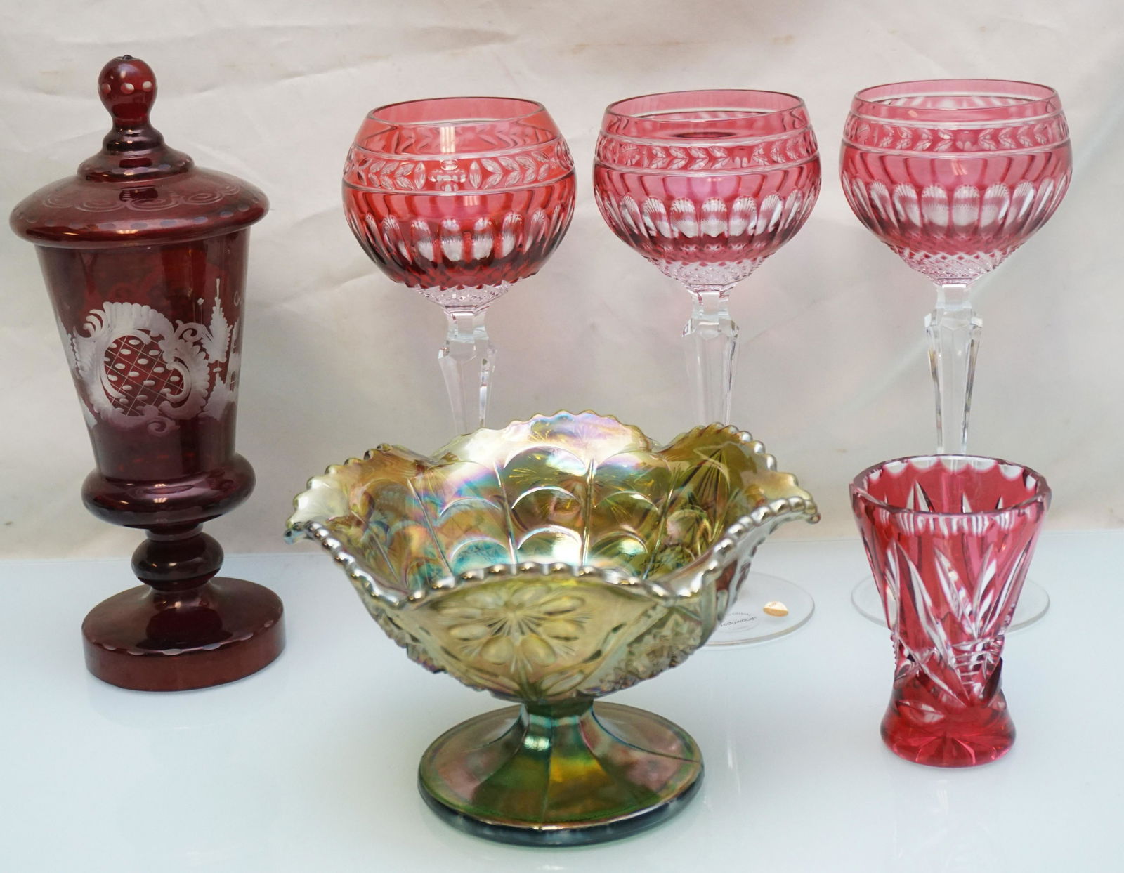 6 pc CRANBERRY & CARNIVAL GLASS: 1- 3 Cranberry Cut to Clear Wedgwood Crystal Wine Hocks made in Germany 8 2/8". 2- Cranberry Cut to Clear Small Vase 3 3/4". 3- Ruby Etched Covered Sweetmeat tiny nick to rim 9". 4- Carnival Glass Imp