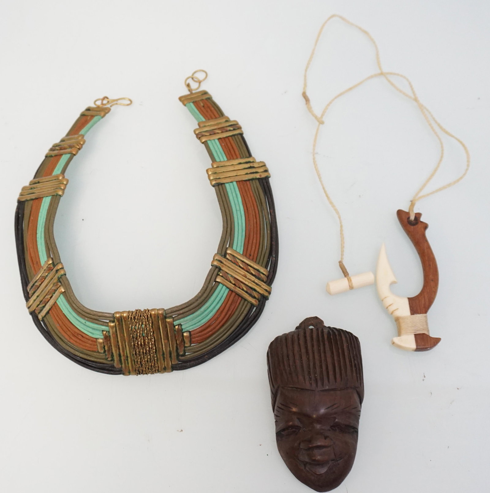ESTATE 3 VINTAGE AFRICAN NECKLACES PENDANT: 1- Tribal Wire and Brass Choker. 2- Wood and Bone Carved Bone Pendant 3" on Cord 19" opened 3- Hard Wood Carved Face Pendant 3 1/4". PROVENANCE: A Charleston SC Private Estate