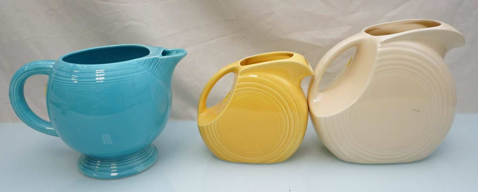 3 1940-50s FIESTA PITCHERS: 1- Old Ivory 7 1/2". 2- Turquoise 64 oz Pitcher 6 1/2". 3- Yellow 5 1/2". Weight on all 6 pds 5 oz.