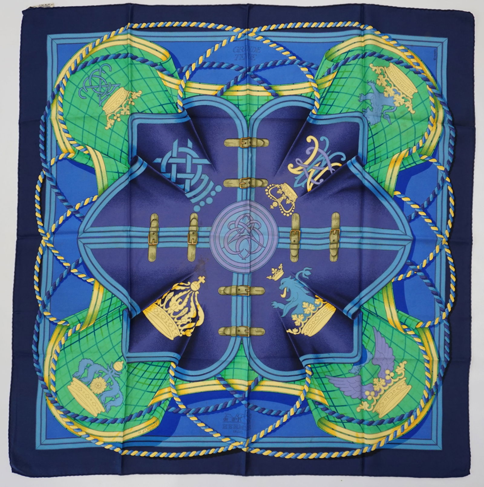 HERMES PARIS "GRANDE TENUE" SILK SCARF: HERMES PARIS silk “Grande Tenue” scarf. The scarf has a center design in purplish blue with gold crowns, royal symbols and is accented with rope designs. It also features a dark blue borde
