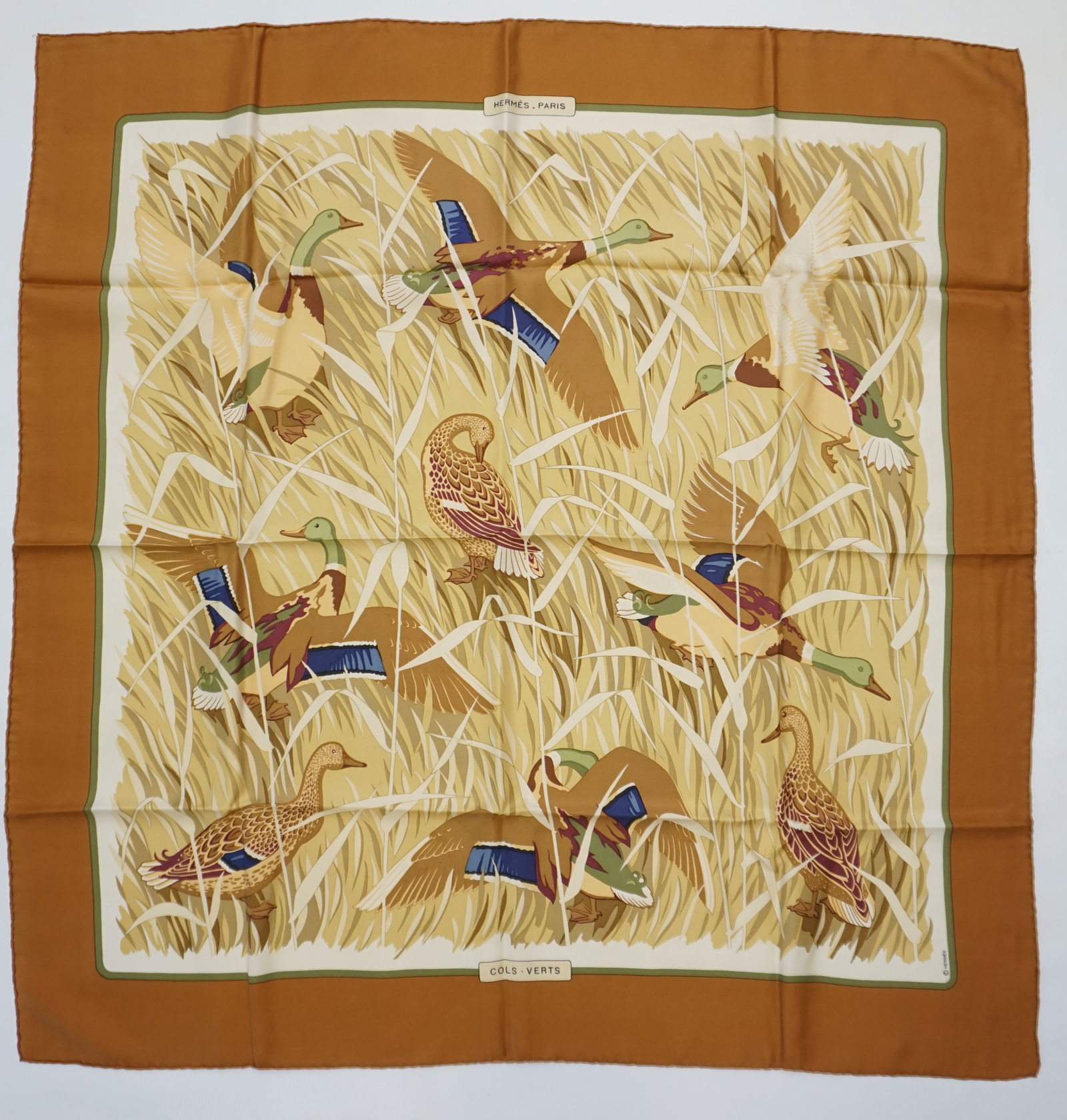 HERMES PARIS "COLS VERTS" SILK SCARF: HERMES PARIS silk “Cols verts” scarf. The scarf features several mallards in brush, some flying away and some landings. The scarf is in muted earth tones and a vivid caramel border. Drawn