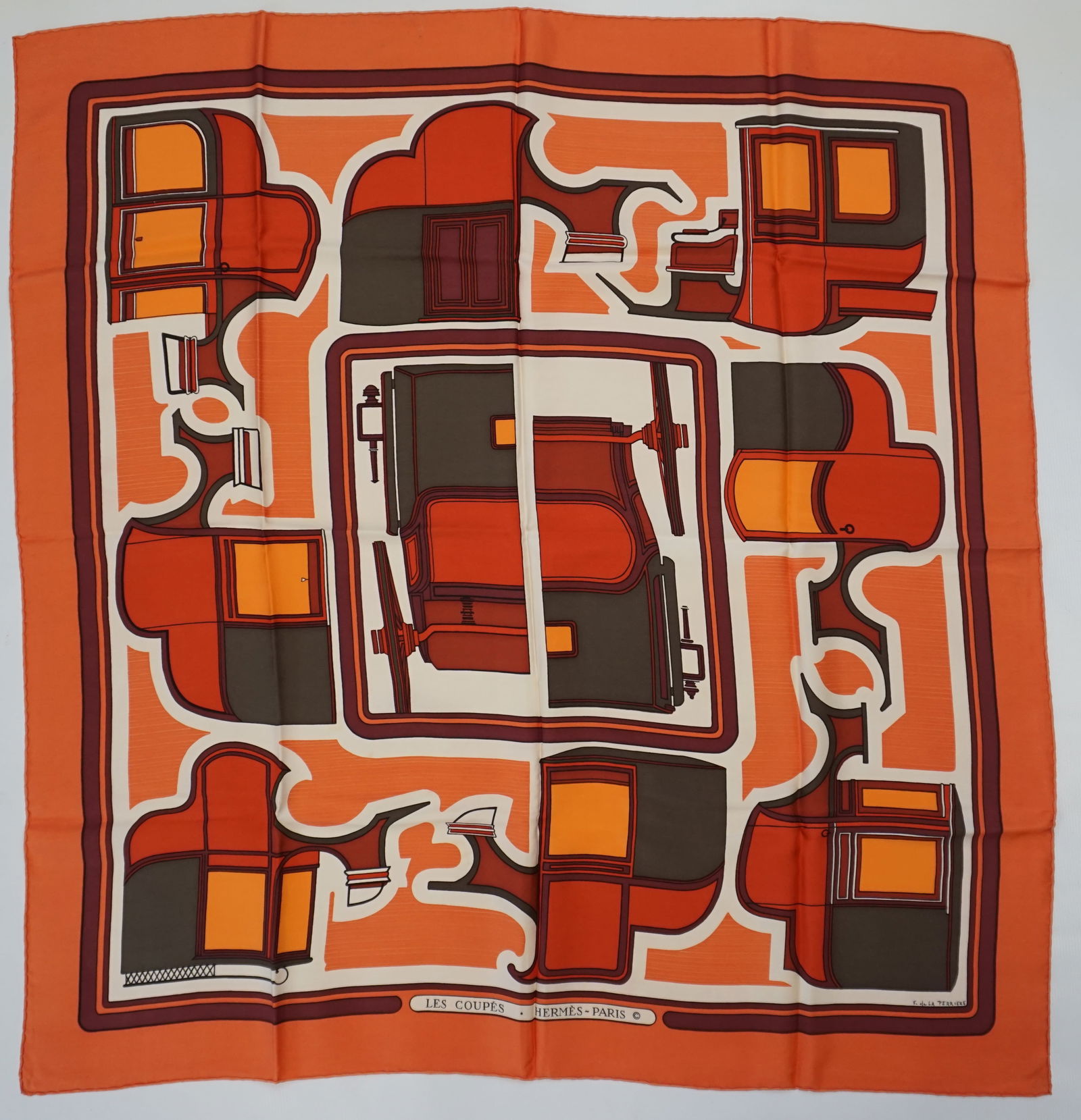 HERMES PARIS "LES COUPES" SILK SCARF: HERMES PARIS silk “les Coupes” scarf. This scarf features carriages as minimalistic shapes geometrically intertwined, in various shades of bright and muted orange, accented by dark taupe d
