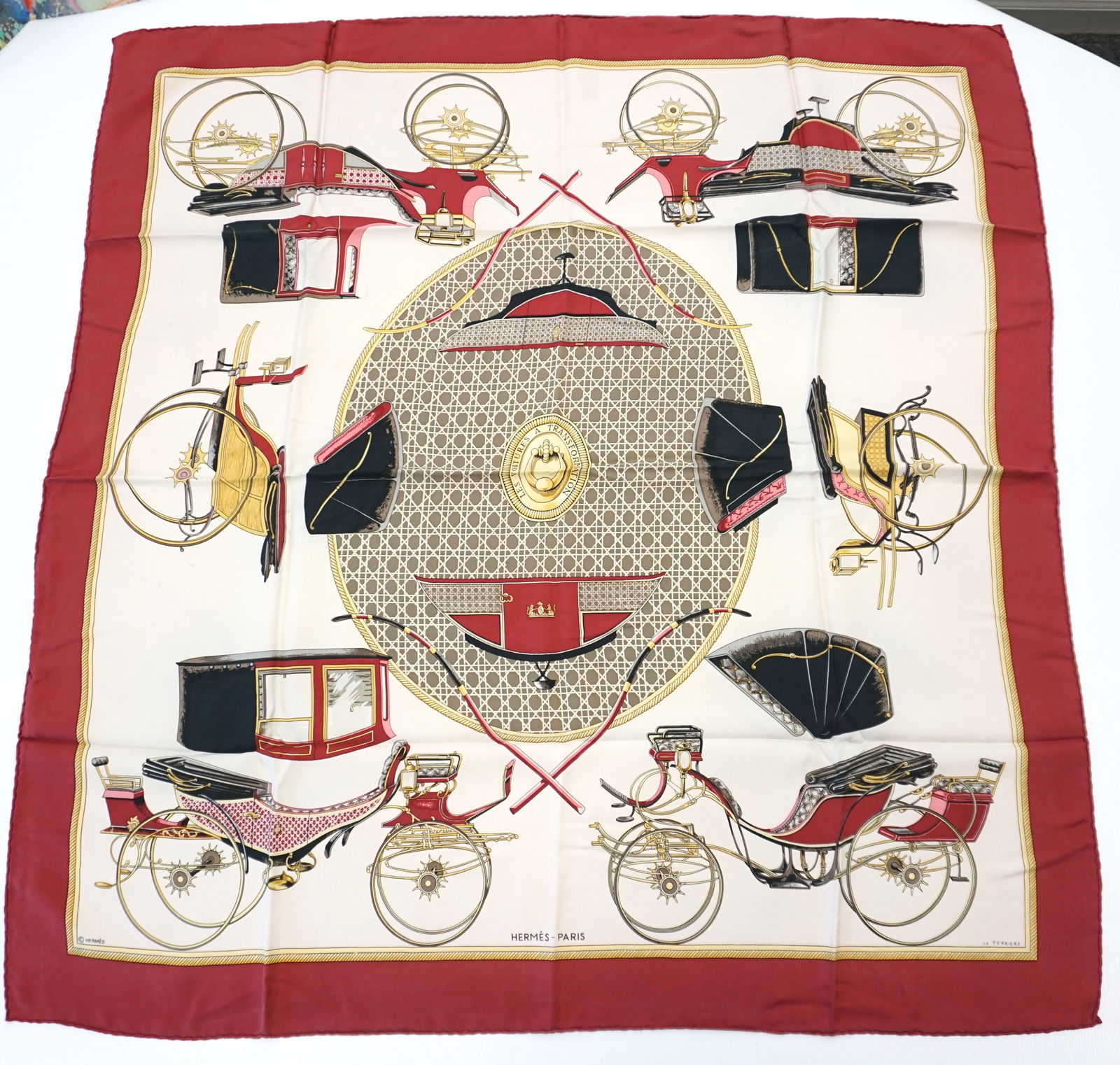 HERMES PARIS "LES VOITURES A TRANSFORMATION" SILK SCARF: HERMES PARIS silk “Les voitures a tranformation” scarf. The scarf features several drawings of various carriages and is centered by oval shaped canework. The scarf shows a muted pink, shad