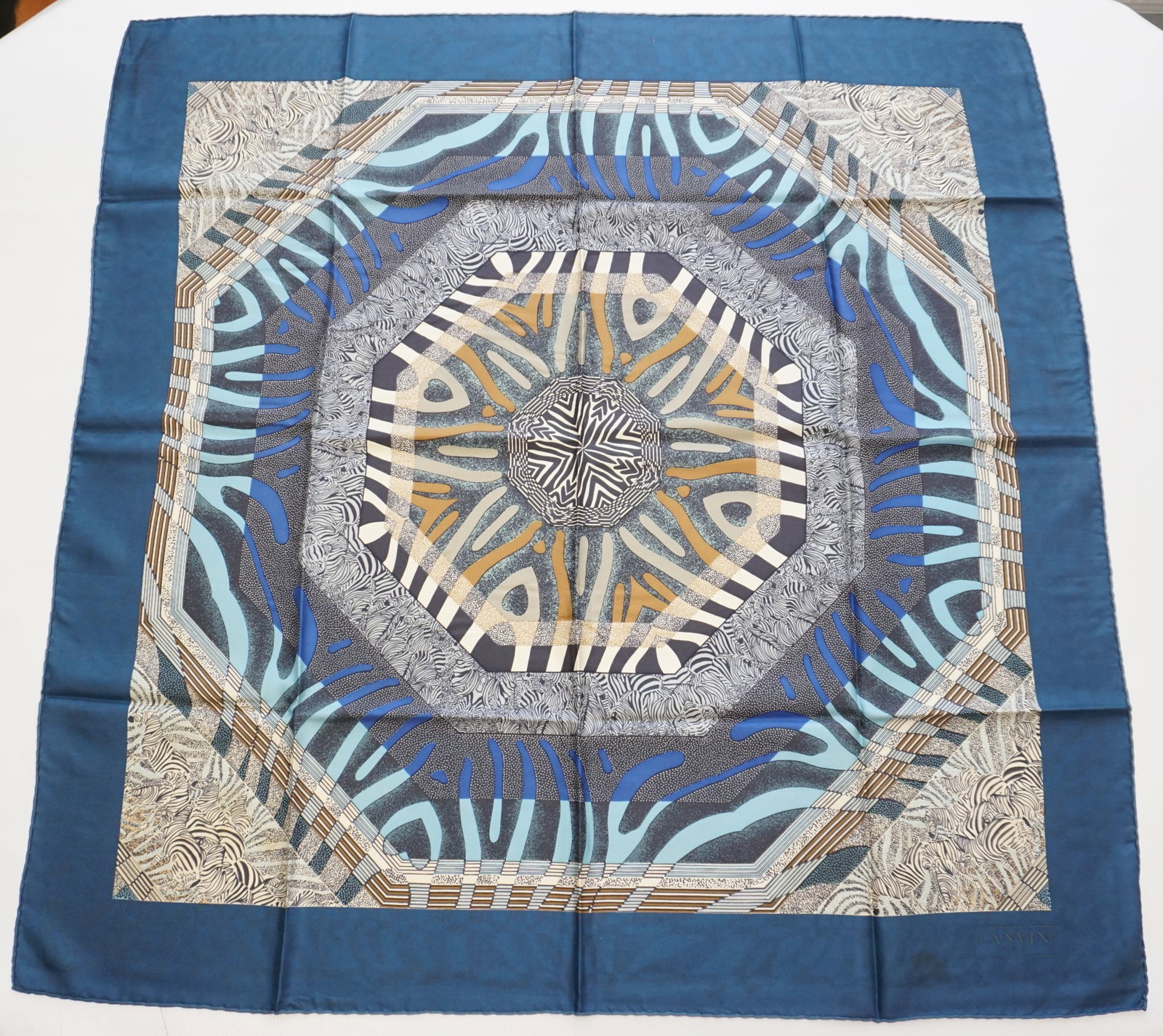 LANVIN SILK SCARF: LANVIN silk scarf featuring geometrical zebra patterns in blue, white, brown, grey and black with a teal border. Sewn in tag present. The scarf measures approximately