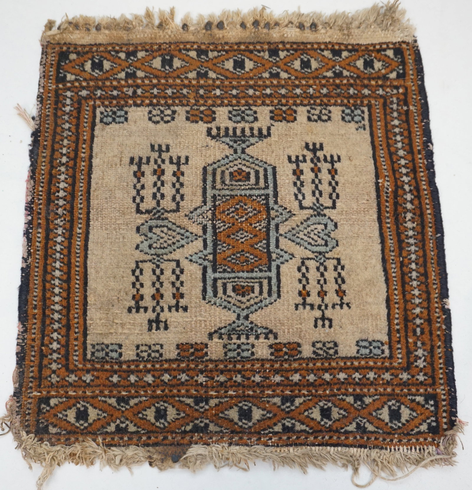 SMALL RUG: The 14" by 13" dimensions of this rug make it a versatile piece for accenting small areas. Age-related wear suggests a well-loved item with a potentially handcrafted origin, adding to its rustic appea