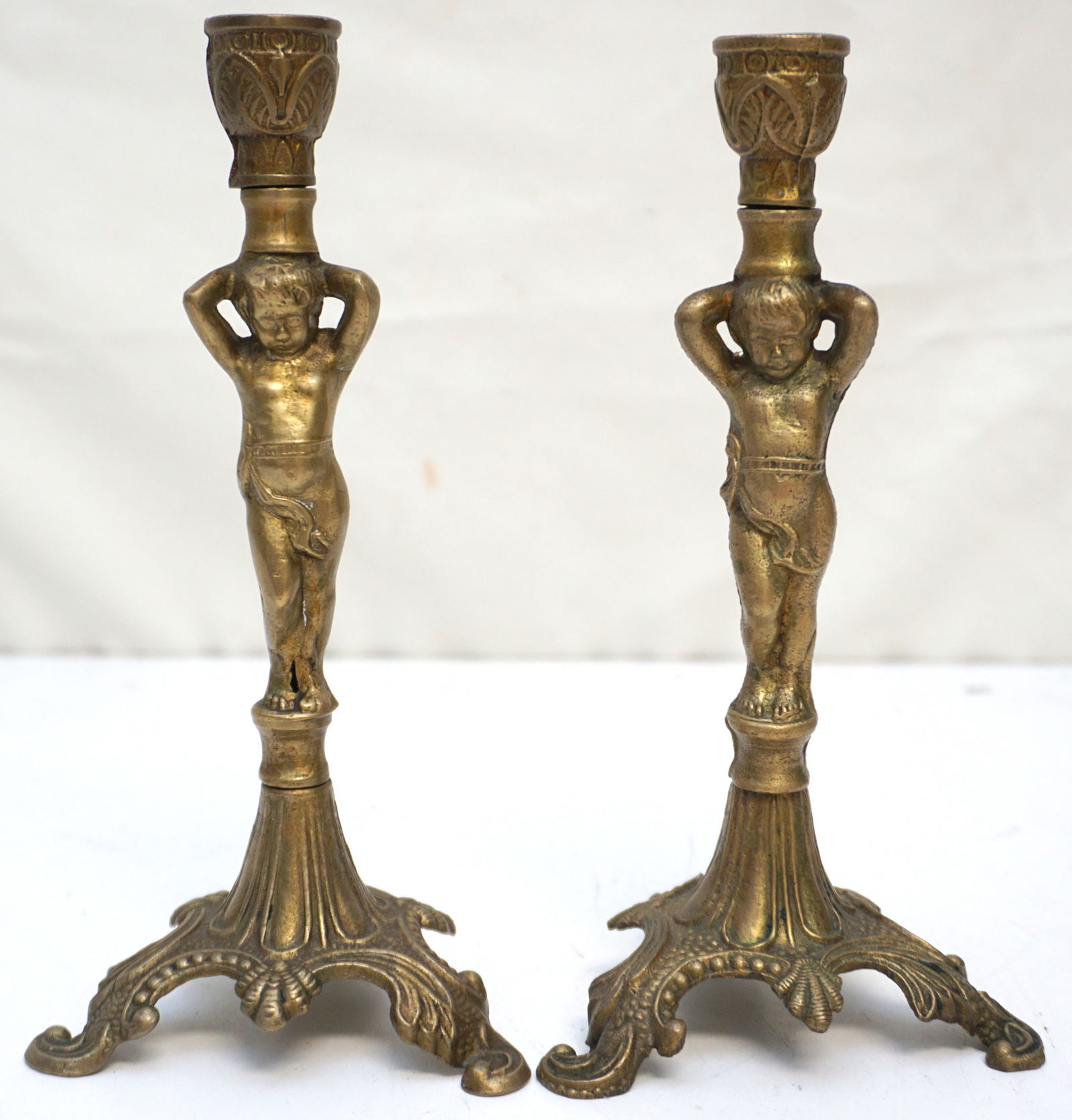 CHERUB-ADORNED ANTIQUE BRASS CANDLESTICKS: A pair of antique brass candlesticks, each graced with a cherubic figure. These candlesticks not only provided light but also served as decorative objects, reflecting the ornate interior design prefer