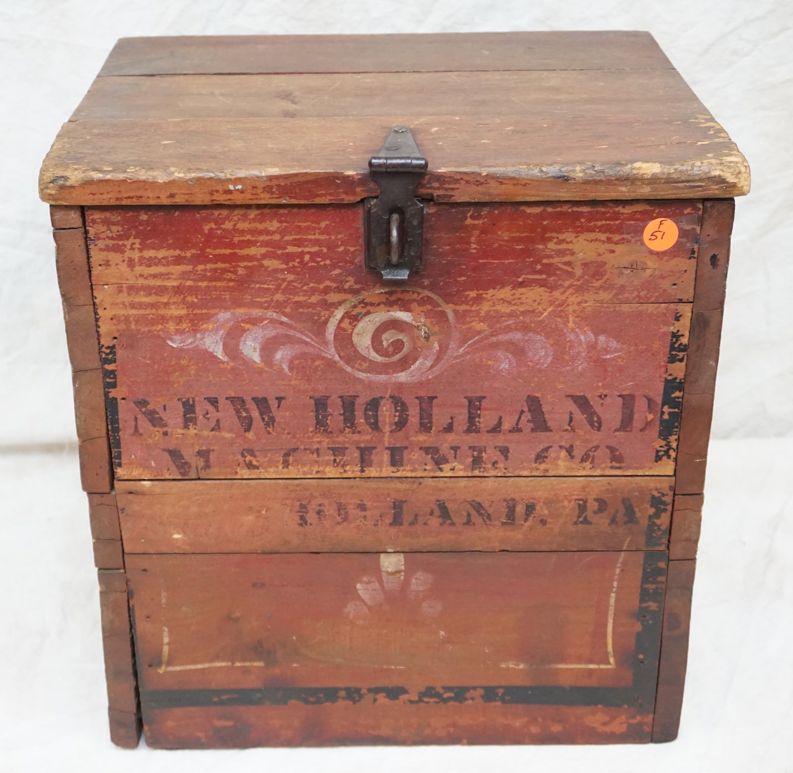 New Holland machine, Co. wooden box: The New Holland Machine Co. wooden box is a robust testament to early industrial branding, featuring original red paint and a clear, stenciled logo that conveys its heritage. The presence of a lock la