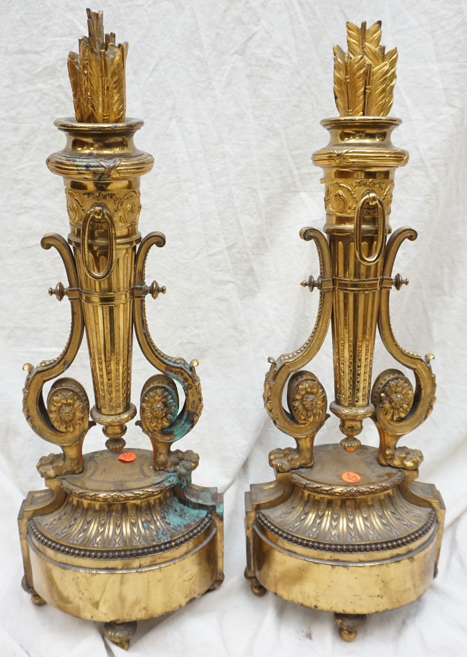 ELABORATE ANDIRONS: Pair of elaborate andirons, each standing at a grand 25" tall with a footprint of 9" x 6". These majestic pieces are crafted with an open design, flaunting a regal golden hue adorned with intricate de