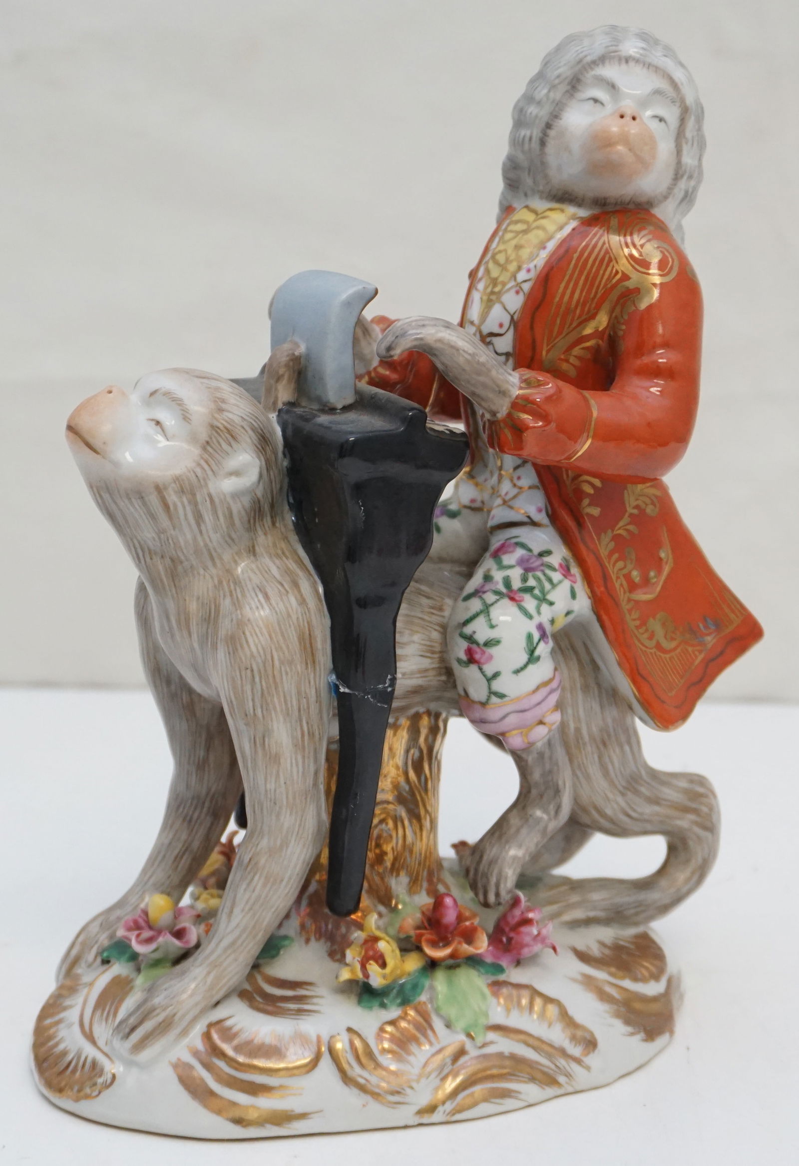 PORCELAIN MONKEY PLAYING PIANO FIGURINE: This charming porcelain figurine stands at 9.5? and depicts a whimsical scene of a monkey dressed in ornate 18th-century attire, playing a piano. The intricate details of the monkey?s attire, includin
