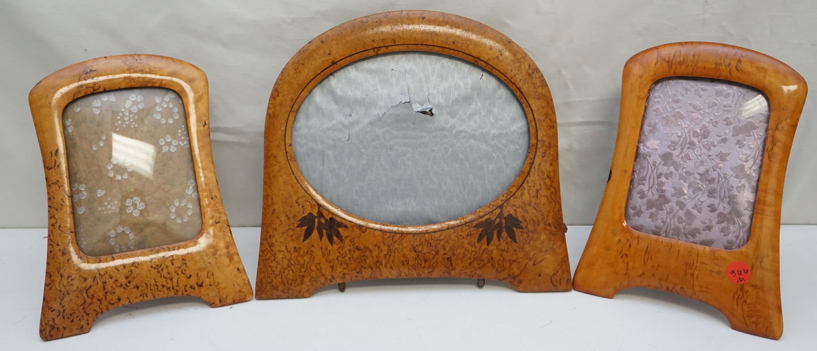 TRIO OF WOOD FRAMES: Trio of ornate picture frames. The frames are designed with a warm, wood-like finish and curved, arched tops, giving them an elegant, vintage look. Each frame contains a different type of decorative i