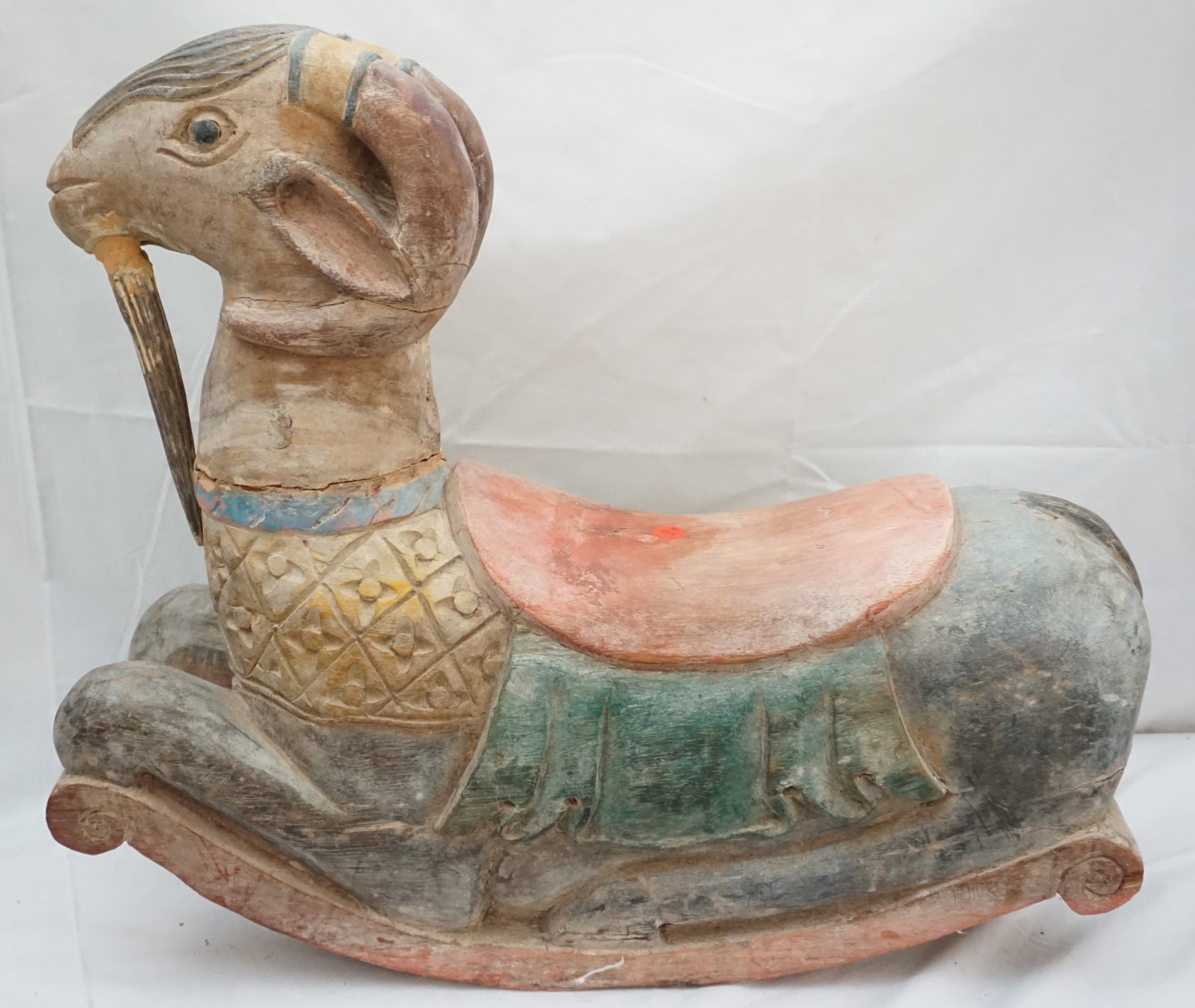 HAND CARVED AND HAND PAINTED RAM ROCKER: Delight in the whimsical charm of this endearing hand-carved and hand-painted ram rocker, bearing the marks of a life well-lived with repairs to its neck. Measuring 24" x 8.5" x 21.5" high, it stands 
