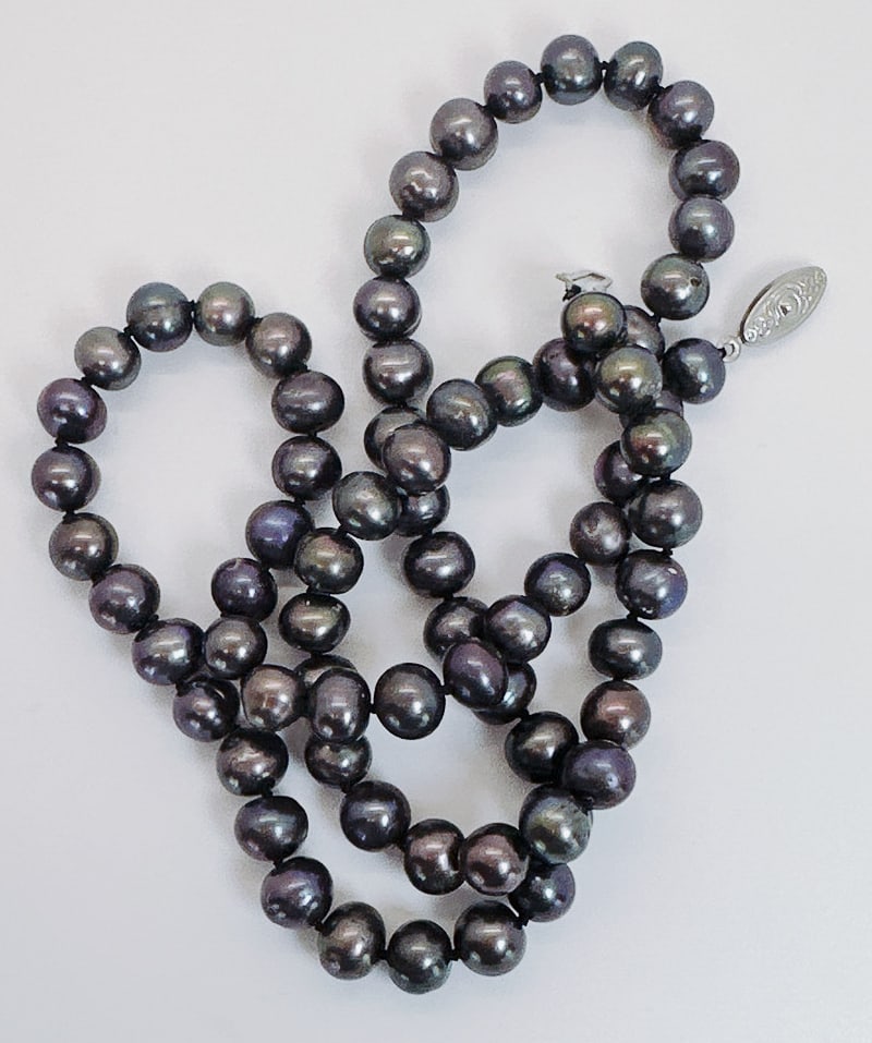 BLACK PEACOCK FRESHWATER PEARL NECKLACE: Adorn yourself with sophistication wearing this black peacock freshwater pearl necklace, gracefully spanning 24 inches. Crafted in an ovalish shape and individually knotted, it exudes timeless charm, 