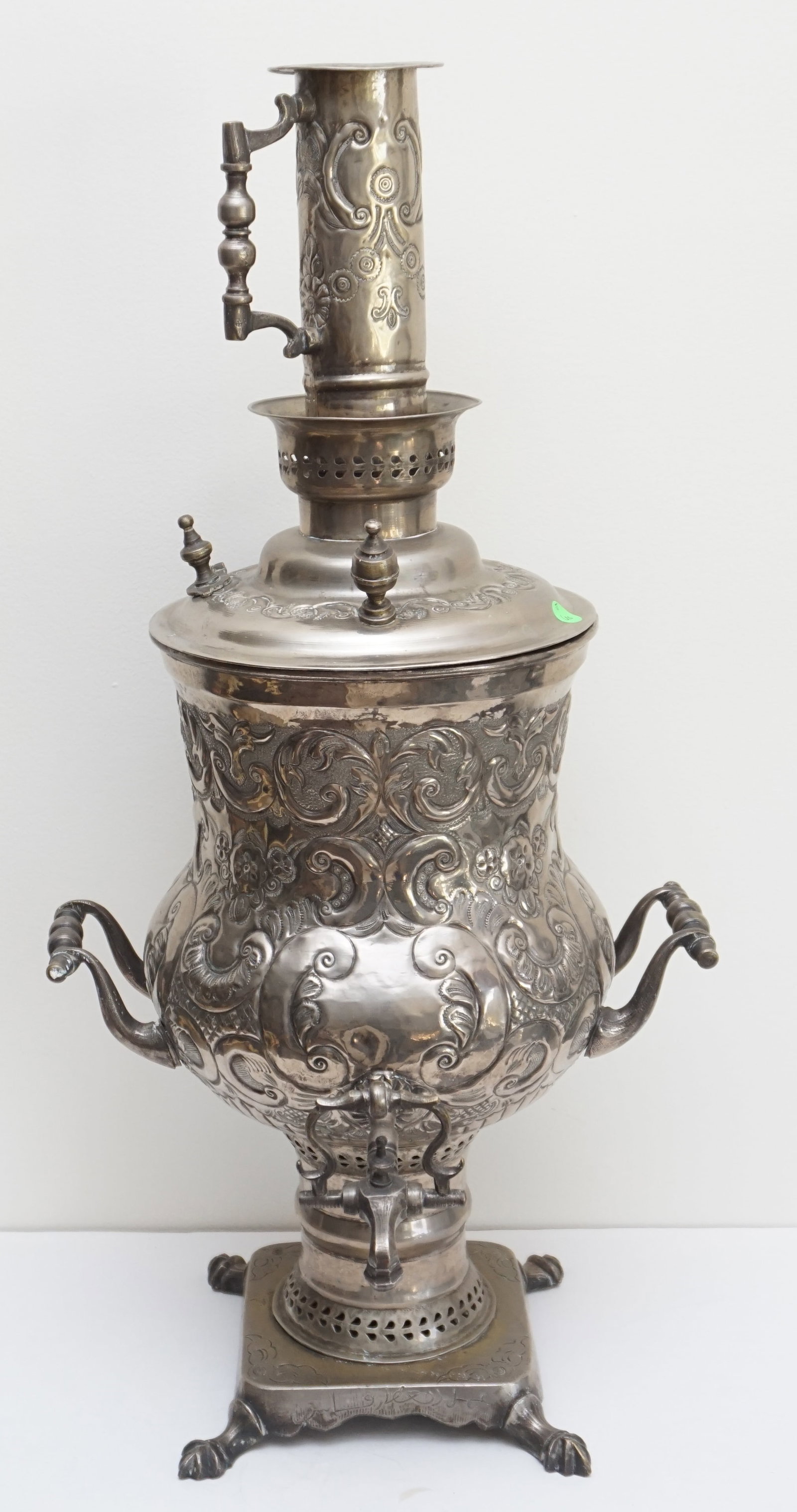 SILVER PLAYE SAMOVAR: This striking antique samovar is a beautiful example of intricate metalwork and timeless design. The samovar features elaborate engravings throughout its body, spout, and chimney, showcasing skilled c