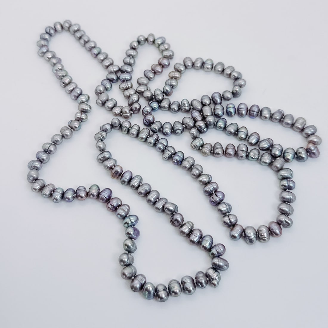 SILVER BAROQUE PEARL NECKLACE, 53": Enhance your ensemble with the sophistication of a freshwater silver baroque ovalish pearl necklace. Delicately knotted at 53", each pearl exhibits a captivating pinkish-green overtone, adding a touch