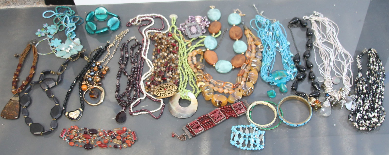VIBRANT COLLECTION OF VINTAGE AND FASHION JEWELRY: A vibrant collection of 24 pieces of vintage and fashion jewelry, including necklaces, bracelets, and earrings. This assortment showcases a variety of styles, from bold statement pieces with chunky be