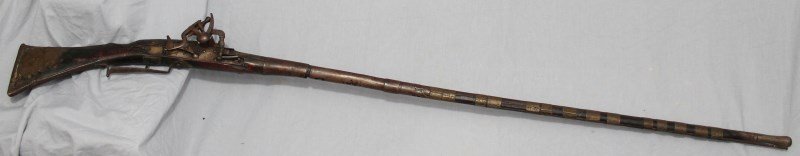 19th c. NORTH AFRICAN SNAPHAUNCE MUSKET: Antique 19th c. North African Snaphaunce Musket. The round barrel is held by 14 hand hammered brass bands and has engraving on the barrel. Broad flared flat barrel end. Measures approximately 51 1/2"