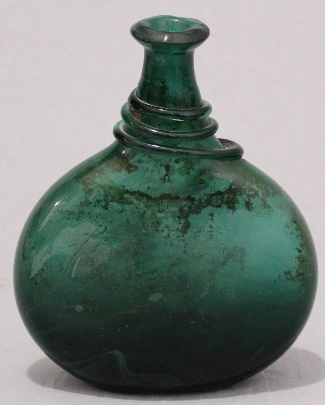 LARGE EMERALD GREEN ANCIENT ROMAN FLASK: Large Green Ancient Roman Blown Glass Flask Bottle. Stunning deep green color, has linear wrap design on neck and double rolled neck. Old bruise/ nick to neck. 9 1/2" tall, 17" circumference. Provenan