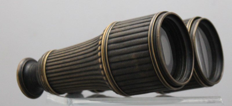 BRASS CASED BINOCULARS - NUGENT WELLS: Antique Brass Cased Binoculars. The finely ribbed brass barrels are particularly attractive. There is a chip to the lens inside, however the optics are still quite sharp and clear. Although we can see